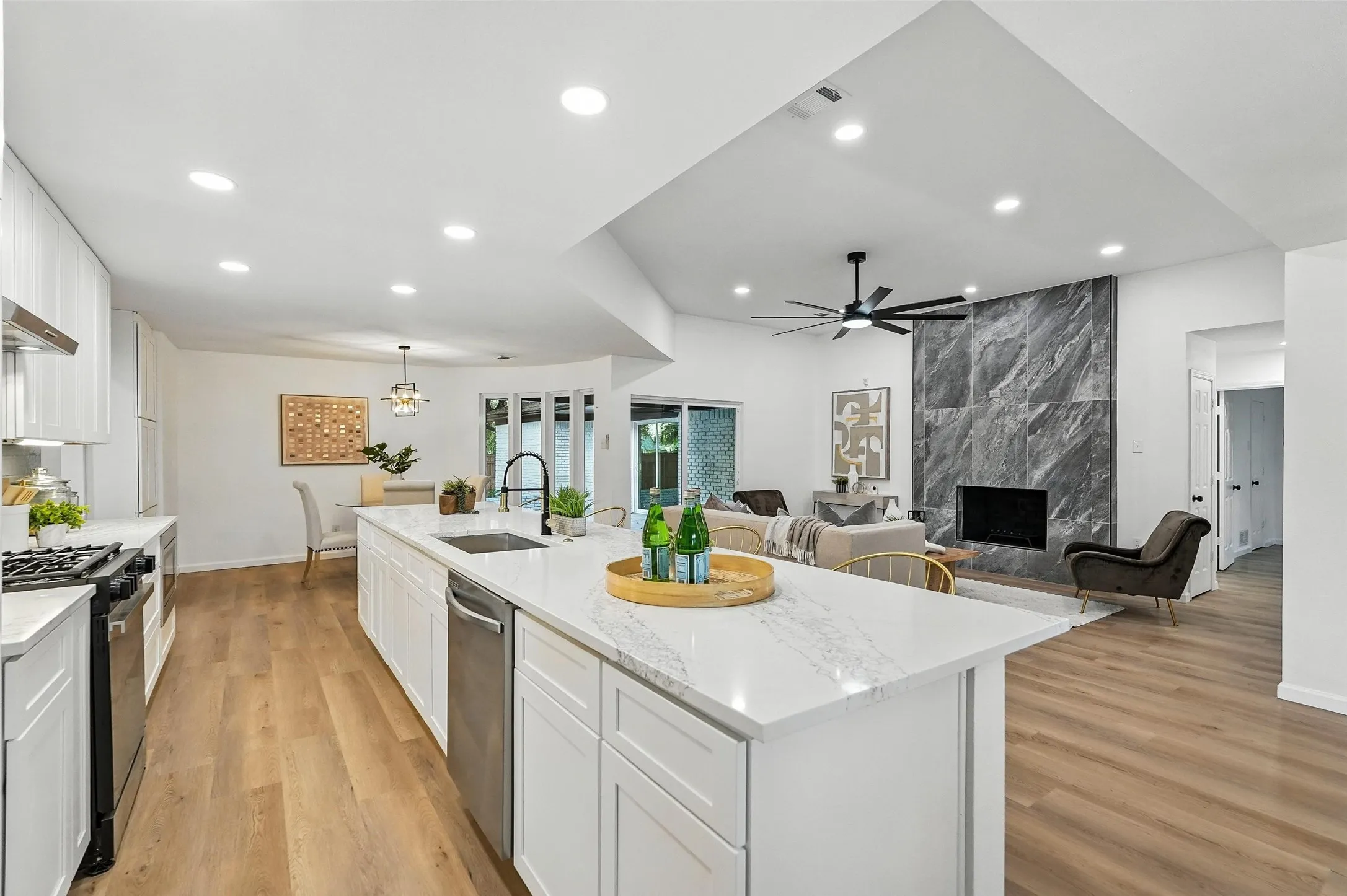Kitchen with gas range, white cabinets, a kitchen island with sink, light wood-style flooring, and recessed lighting