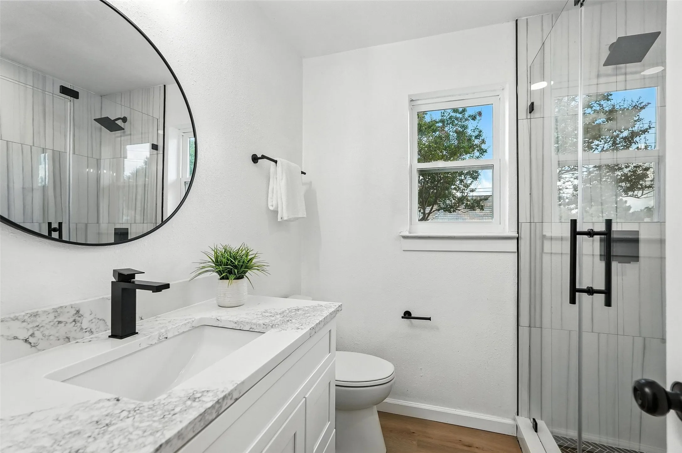 Full bath featuring a shower stall, vanity, wood finished floors, and baseboard heating