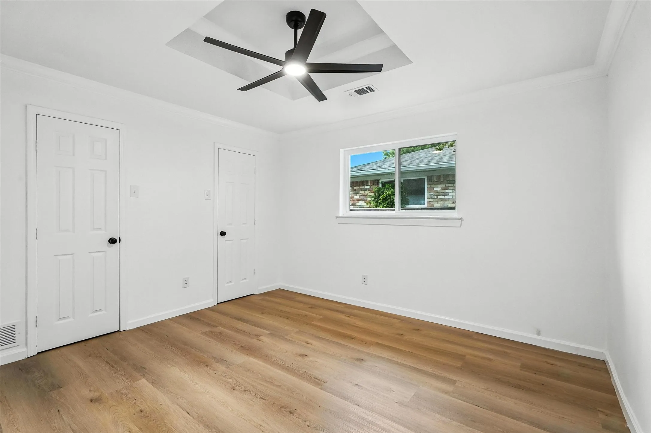 Unfurnished bedroom with crown molding, light wood-style floors, and a ceiling fan