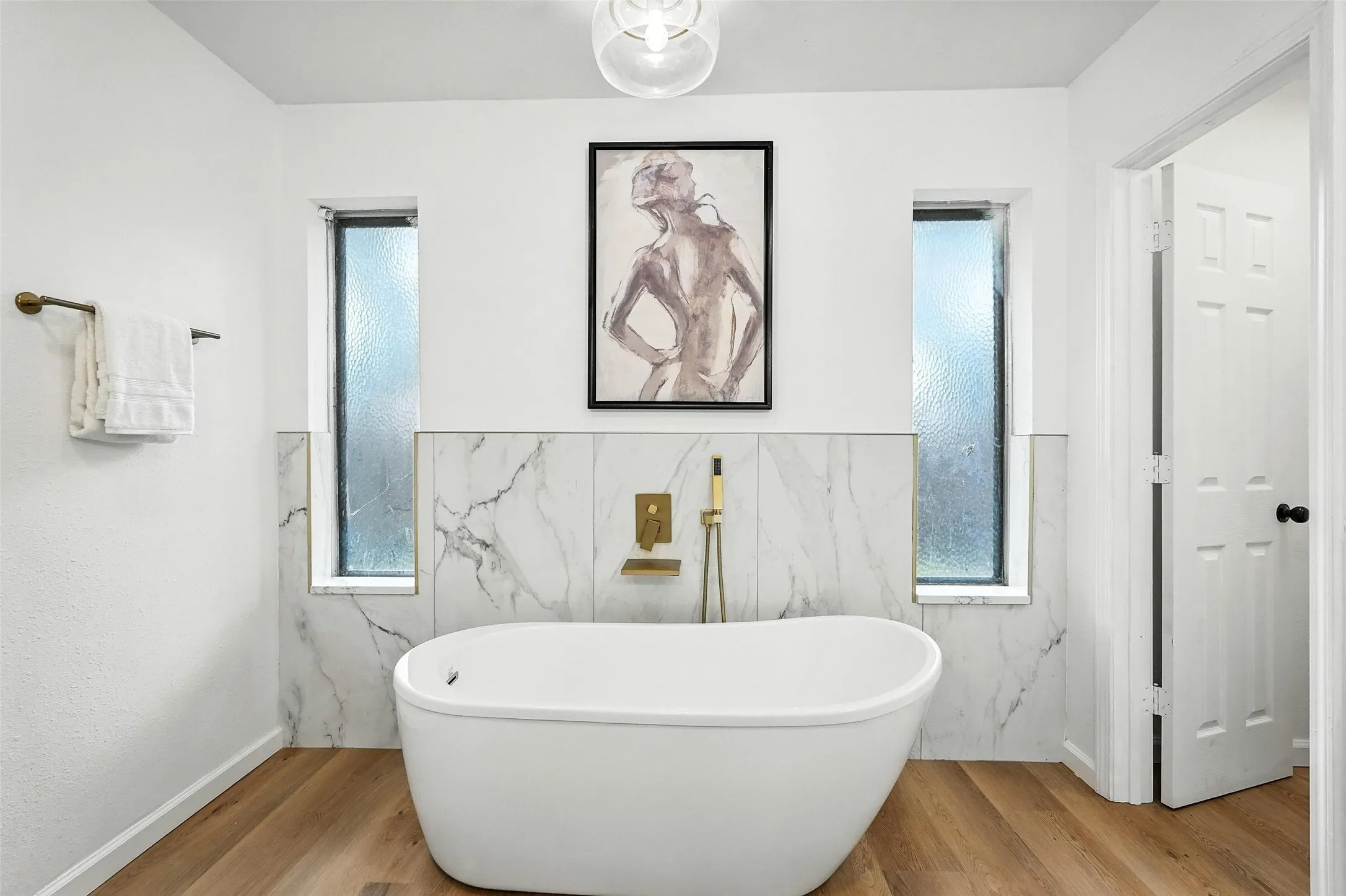 Full bath featuring a freestanding bath and wood finished floors