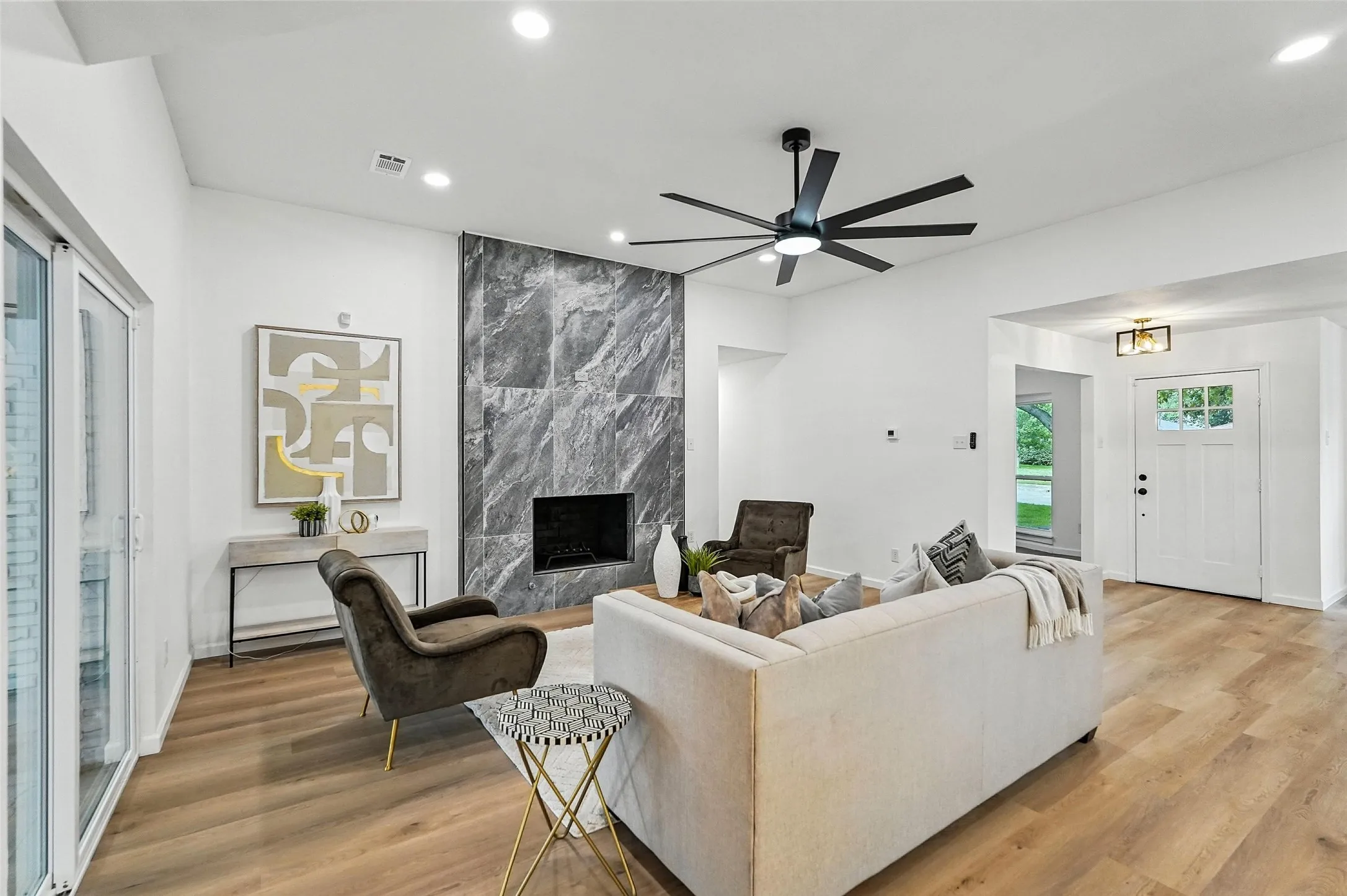 Living room with a premium fireplace, light wood-style floors, ceiling fan, and recessed lighting