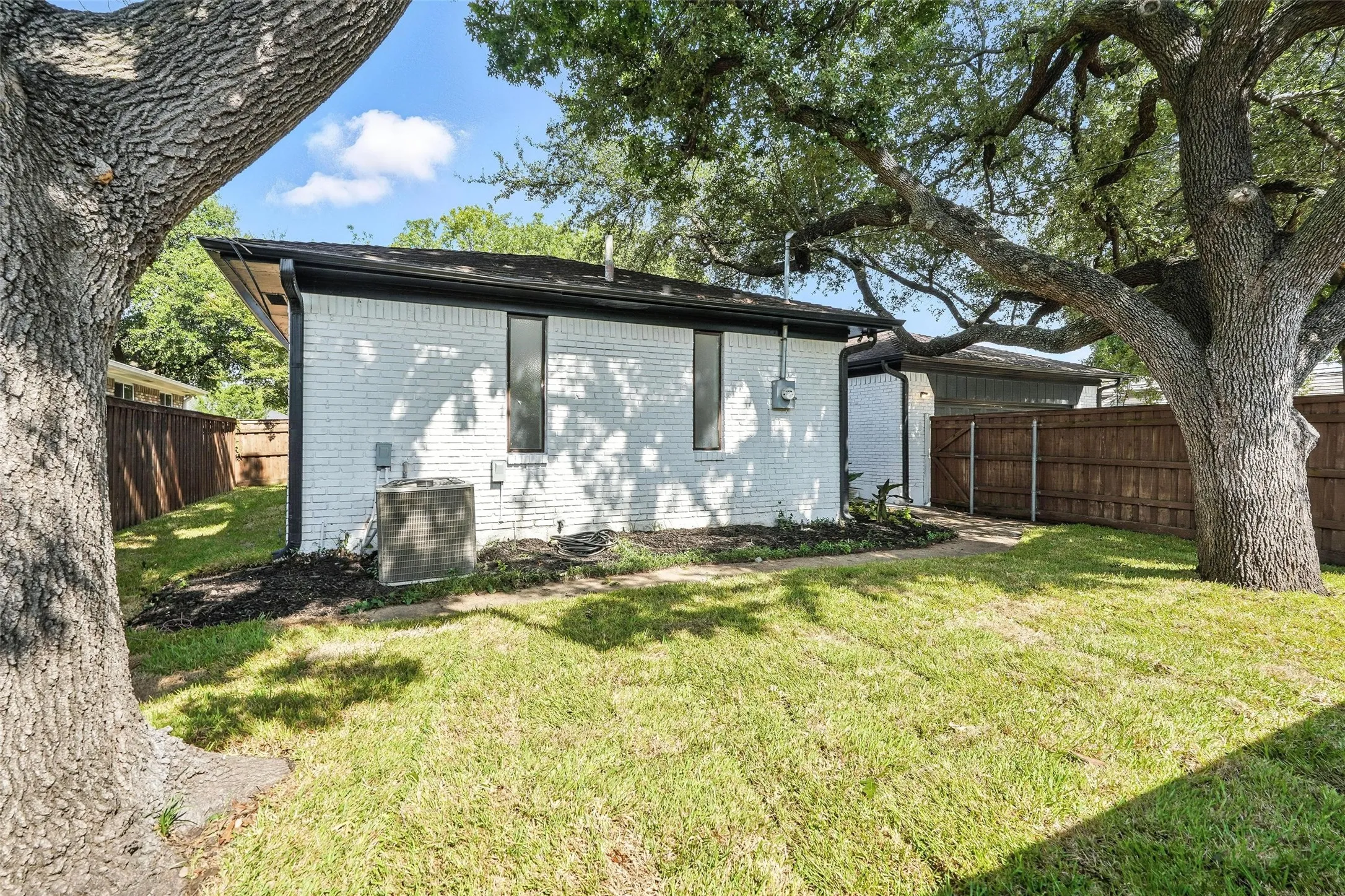 Back of property with brick siding and a fenced backyard