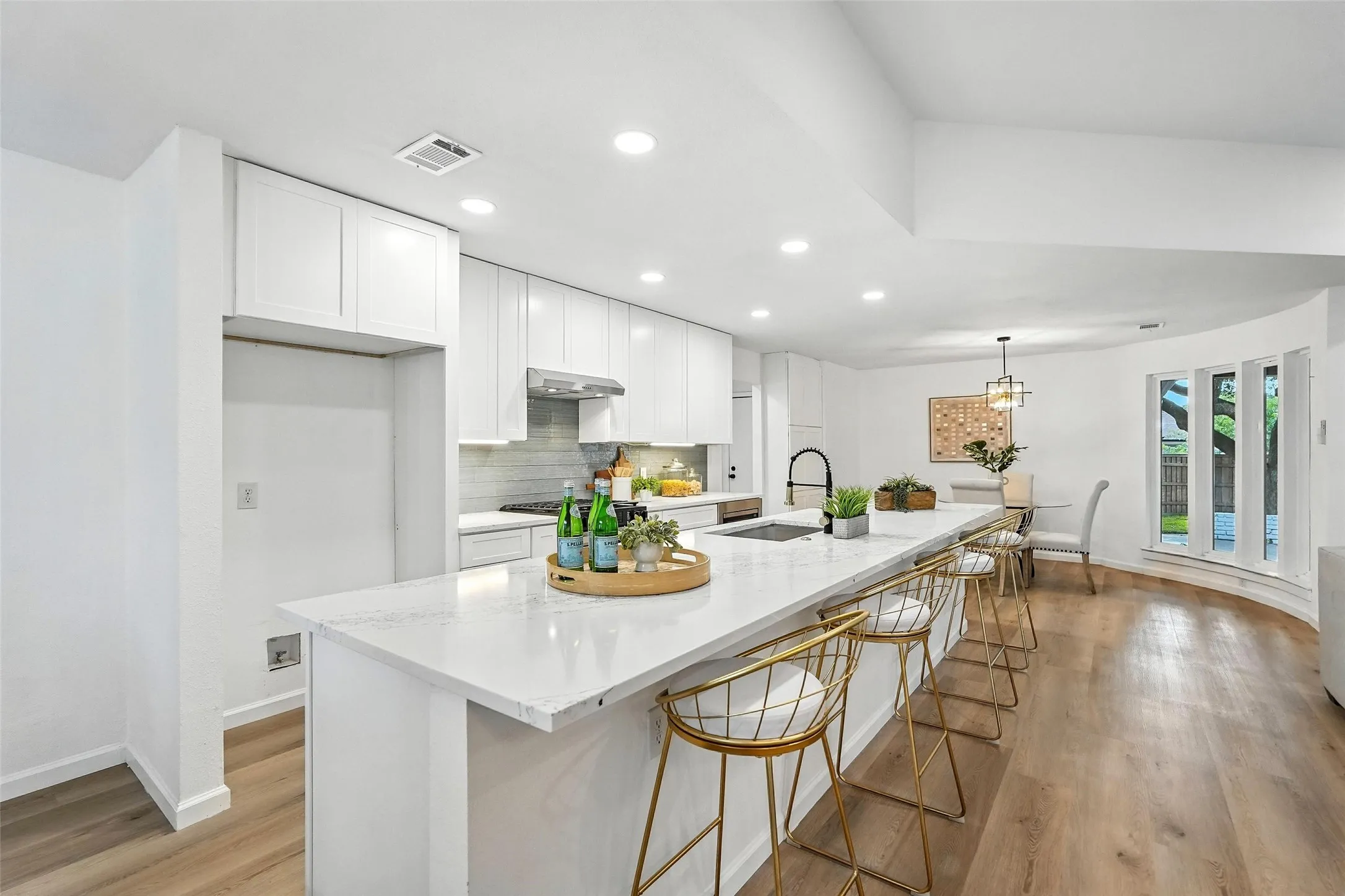 Kitchen with tasteful backsplash, recessed lighting, light wood-style floors, white cabinetry, and a spacious island