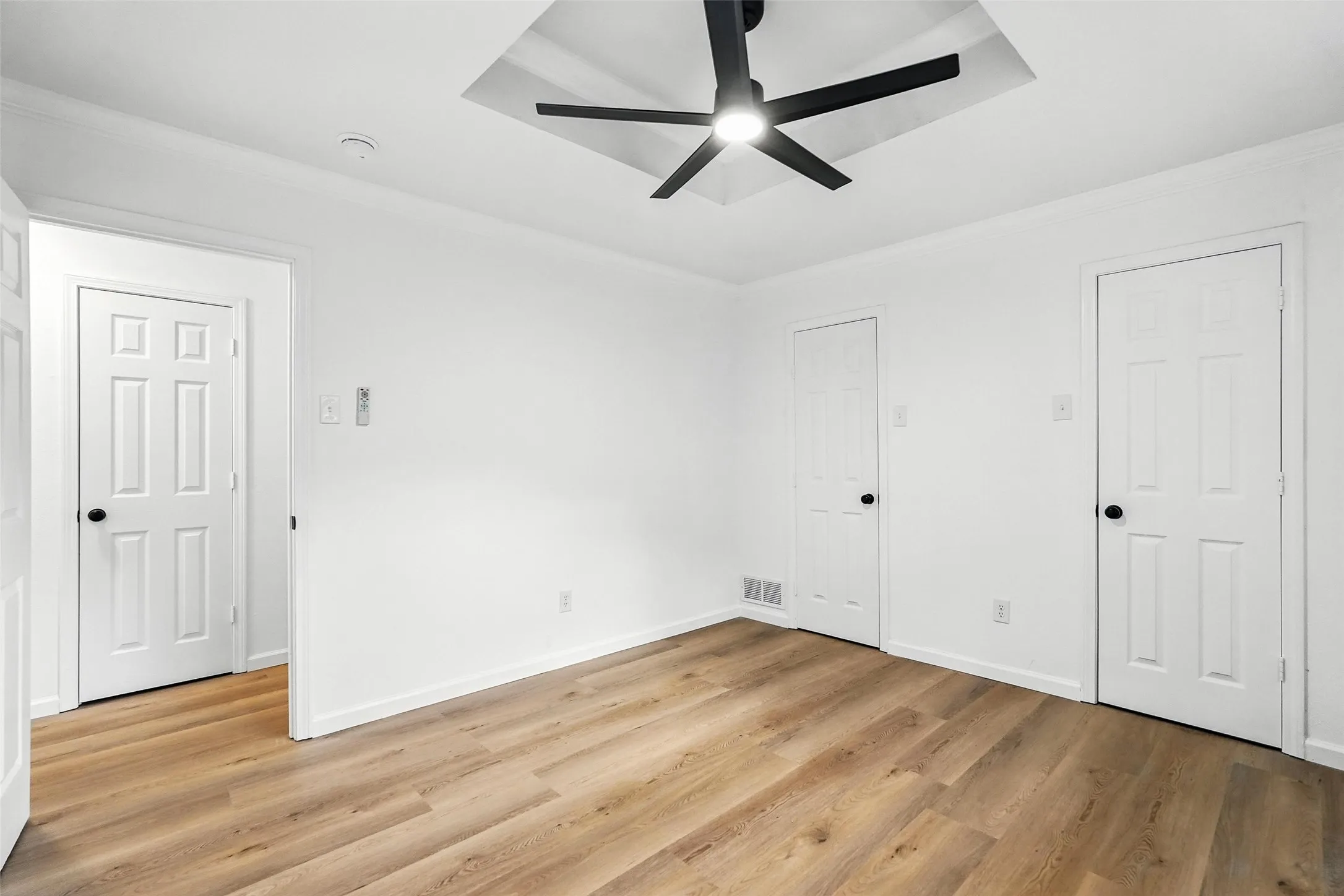 Unfurnished bedroom with ornamental molding, light wood-type flooring, and ceiling fan