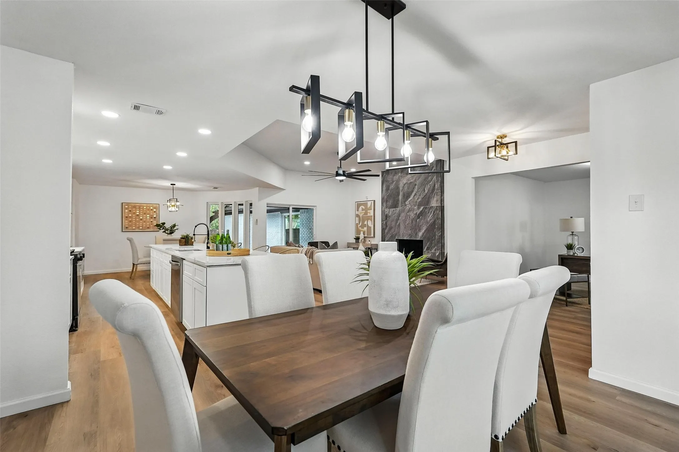 Dining room featuring light wood-type flooring, a fireplace, a ceiling fan, and recessed lighting