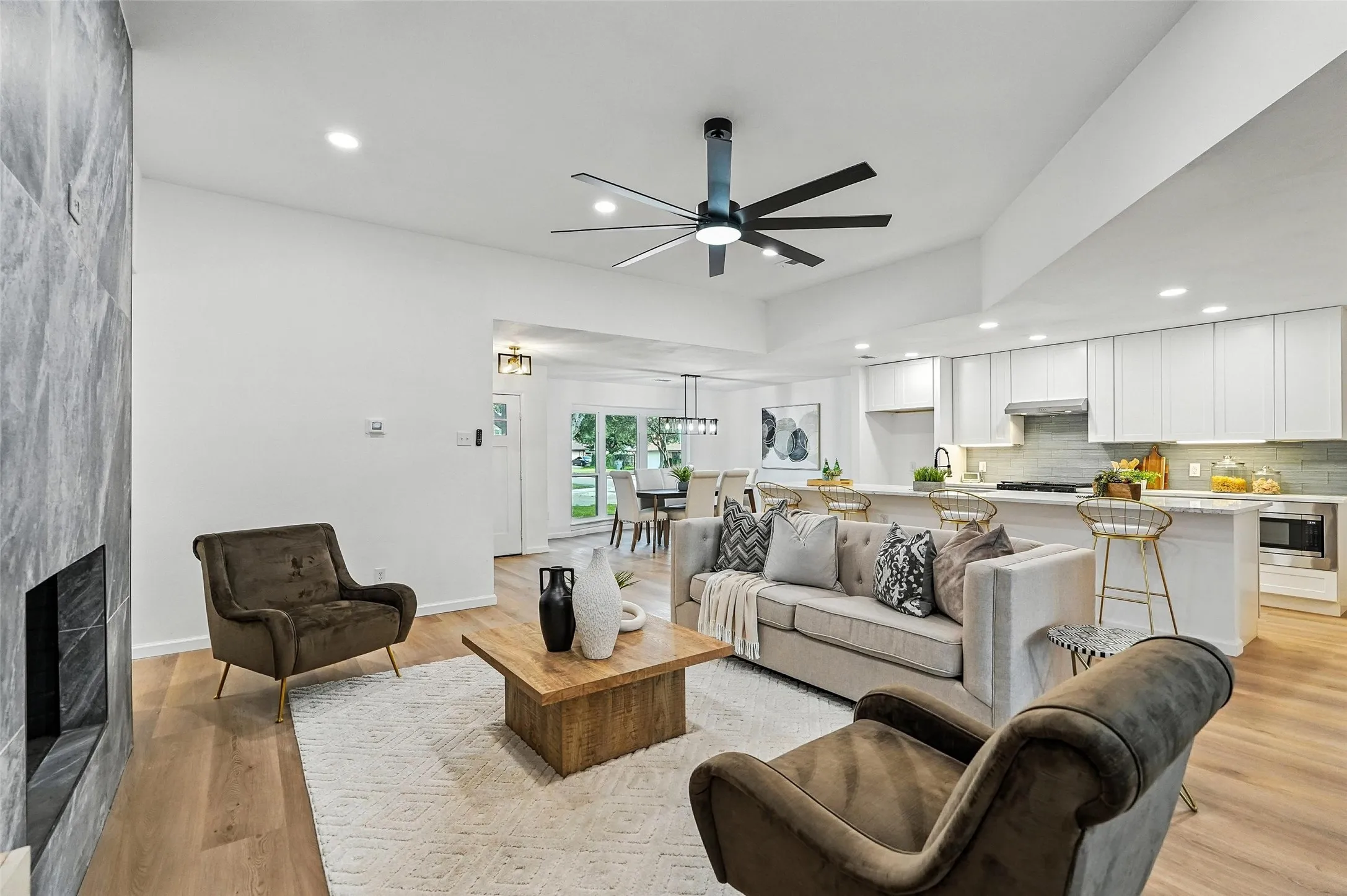 Living area featuring recessed lighting, a large fireplace, light wood-style floors, and ceiling fan