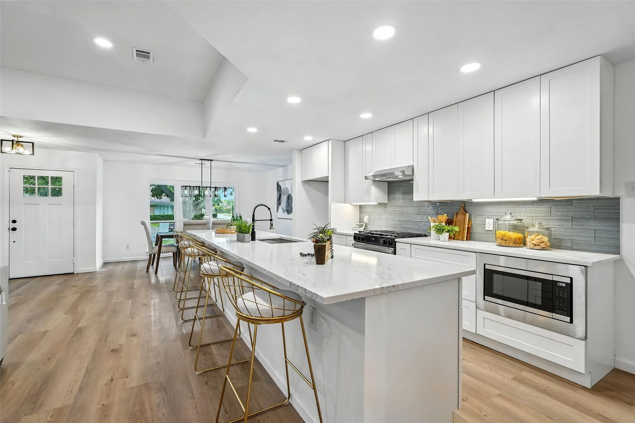 Kitchen featuring recessed lighting, decorative backsplash, white cabinetry, and light stone counters