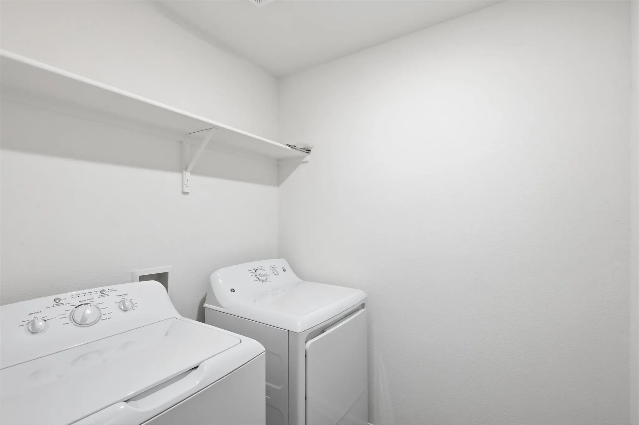 Dedicated laundry area with a white shelving unit for storage