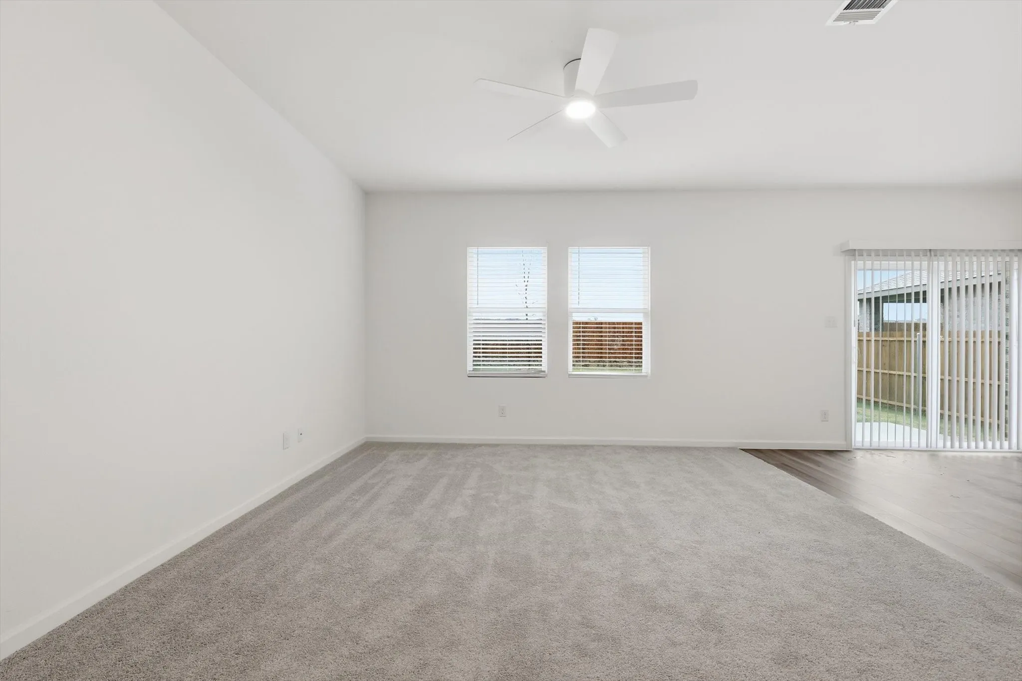 Spacious room featuring light gray carpeting and white walls