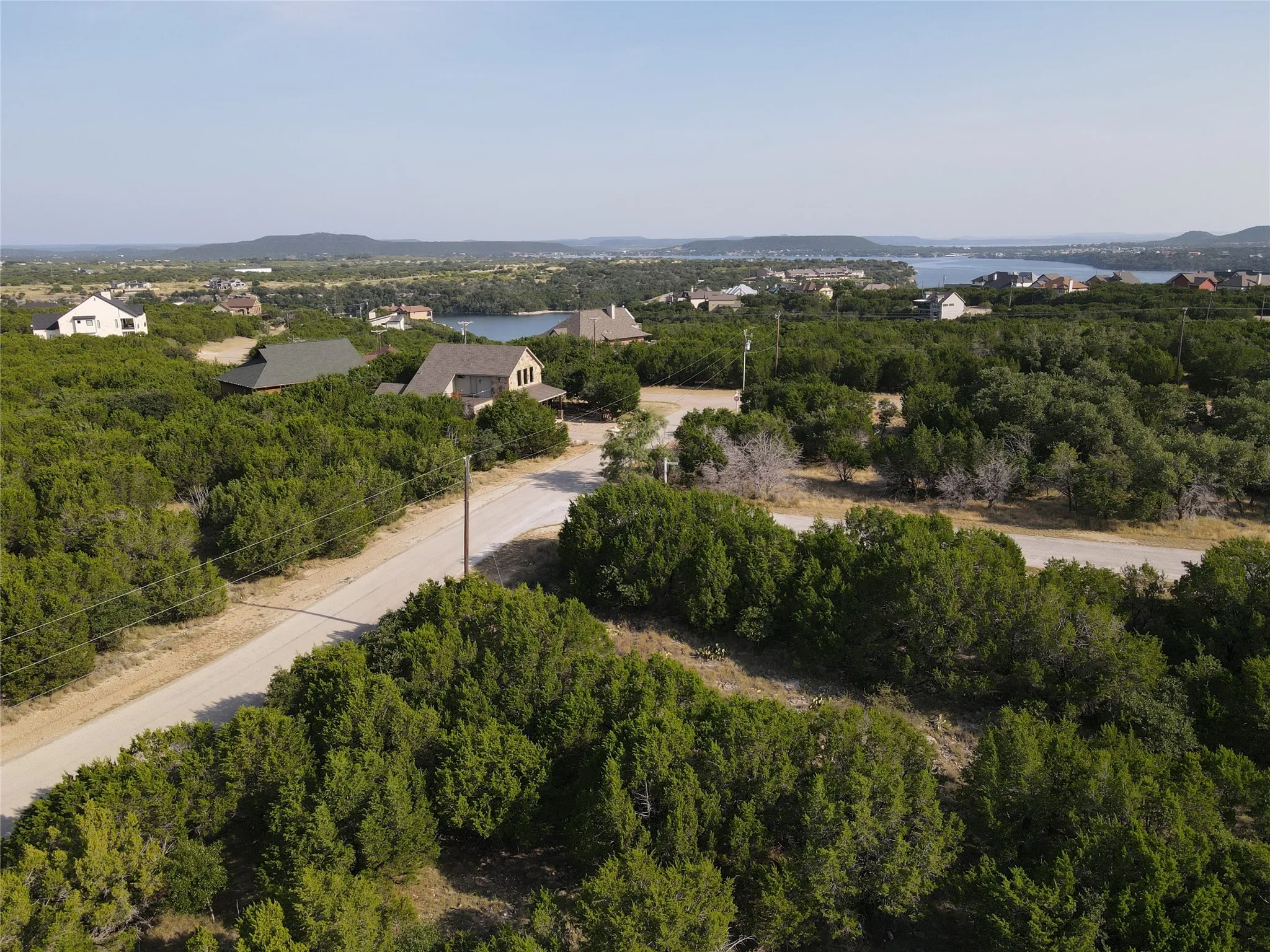 Expansive elevated property featuring a clear sky, distant body of water, and surrounding greenery