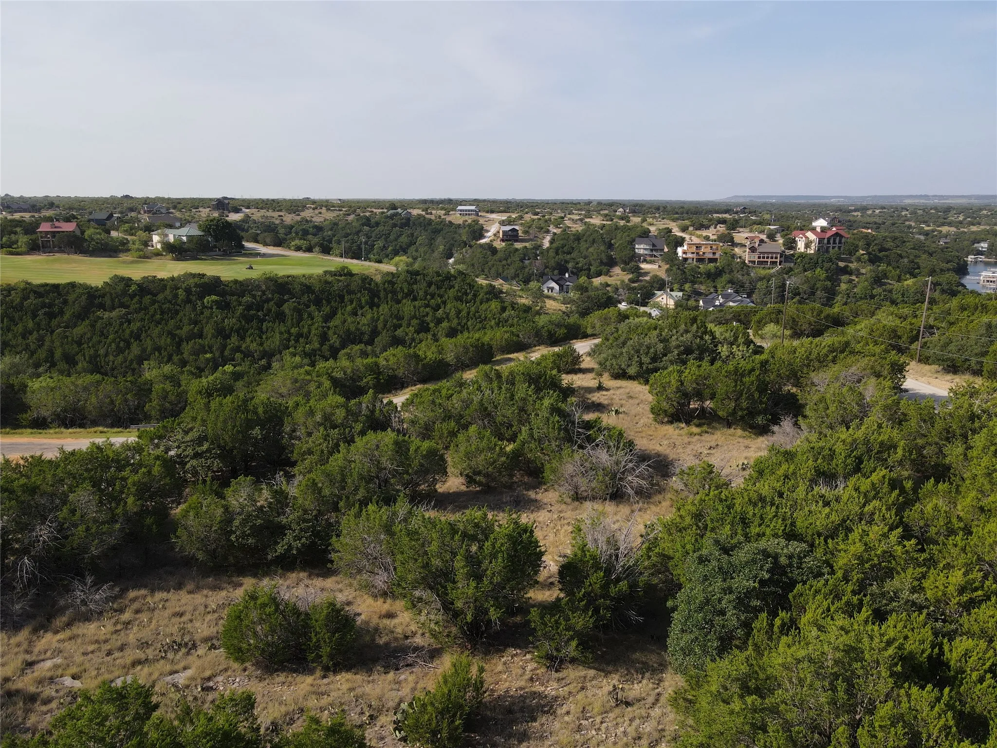 Expansive natural landscape featuring varied topography, mature trees, and a distant body of water