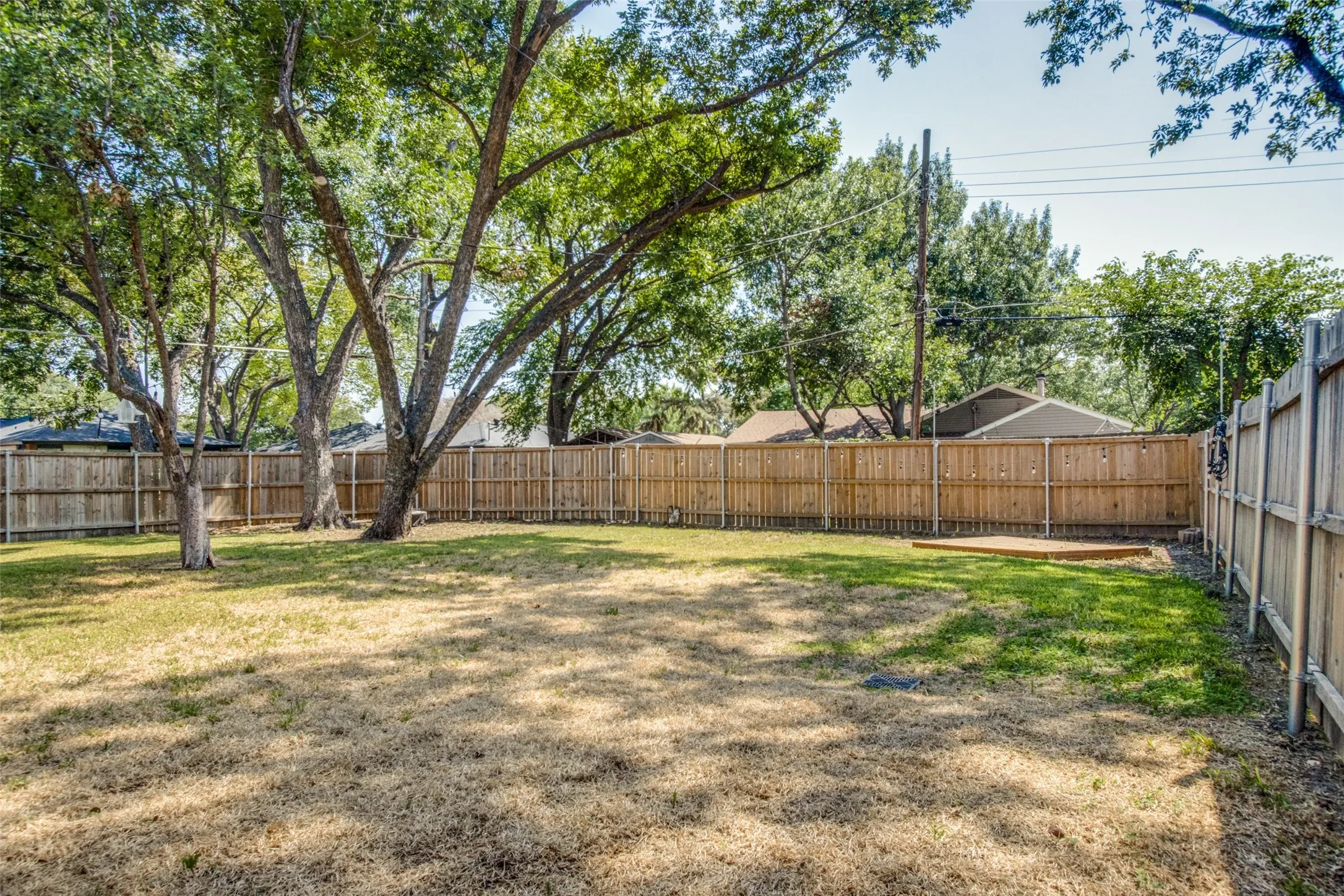 Expansive backyard with a full wood privacy fence and mature trees
