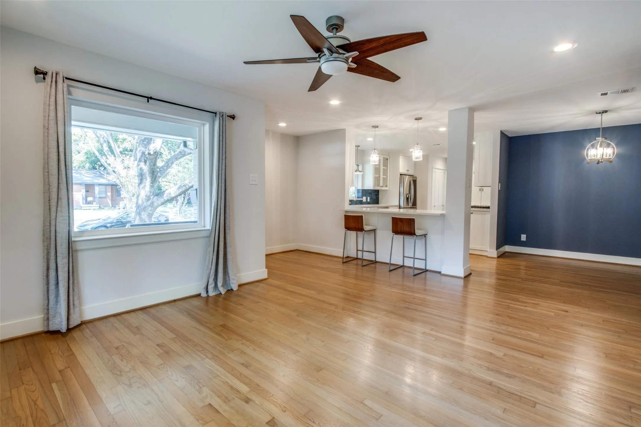 Spacious living area featuring wood-finish flooring, a large picture window, and a ceiling fan