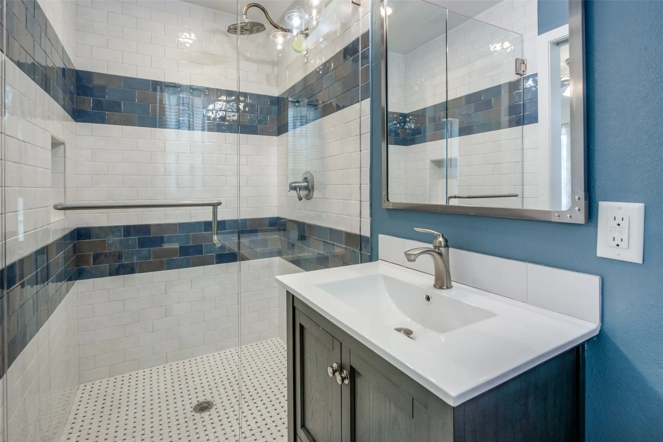 Modern bathroom featuring a walk-in shower with white subway tile and blue accent banding