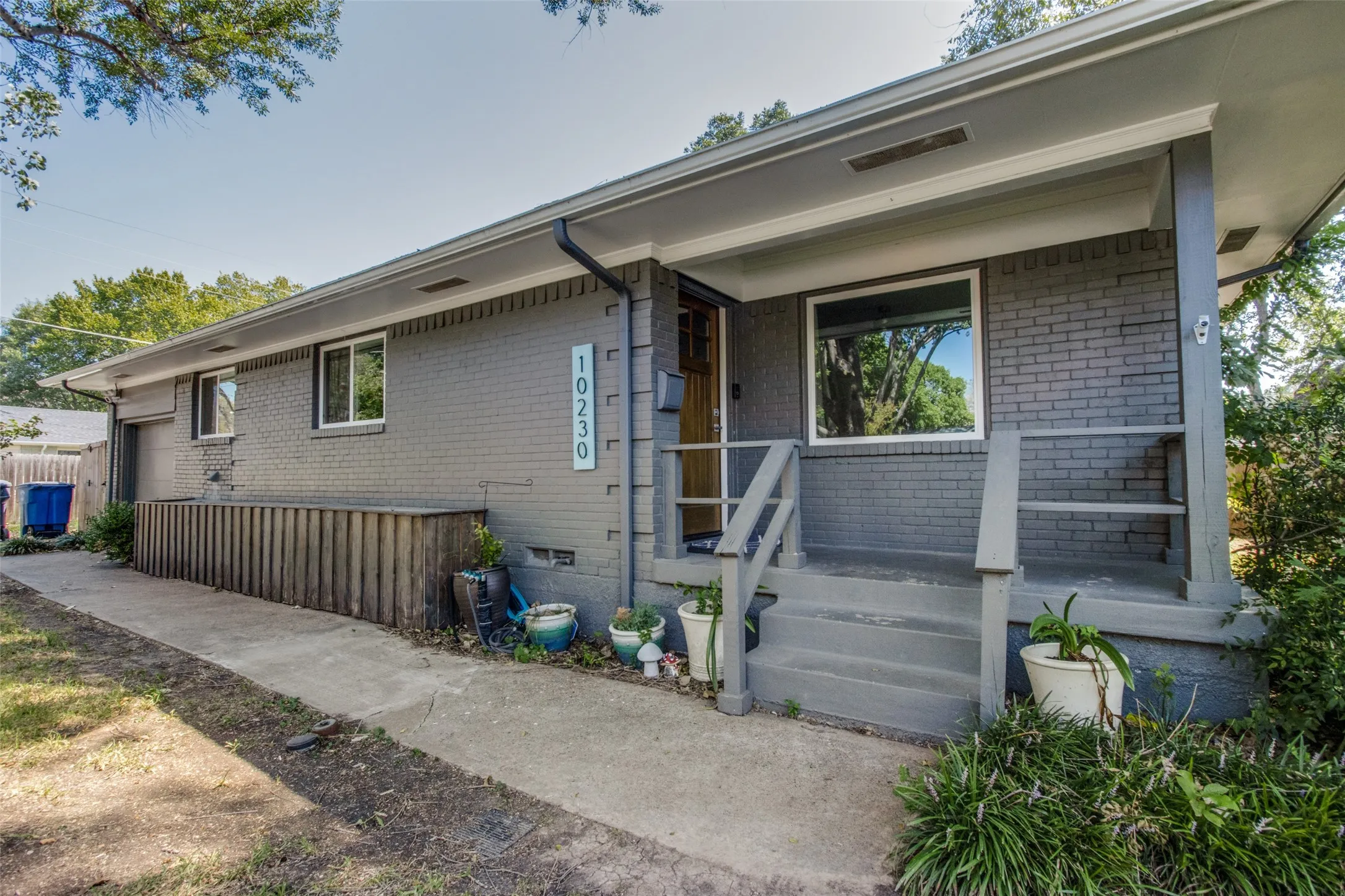 Brick exterior with a covered front porch featuring concrete steps and wood railings