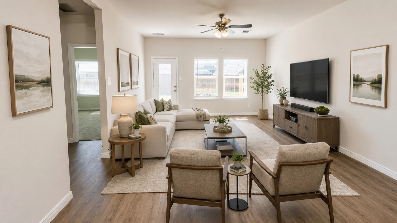 Spacious living area featuring wood-finish flooring, light-toned walls, and abundant natural light from multiple windows