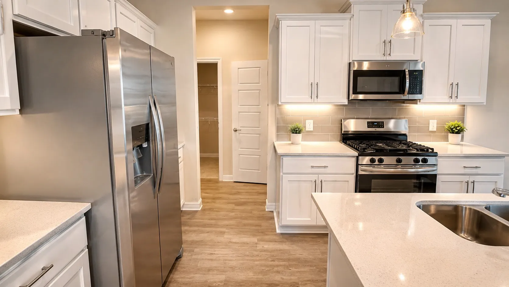 Contemporary kitchen featuring white shaker cabinetry, stainless steel appliances, light-toned countertops, and wood-finish flooring