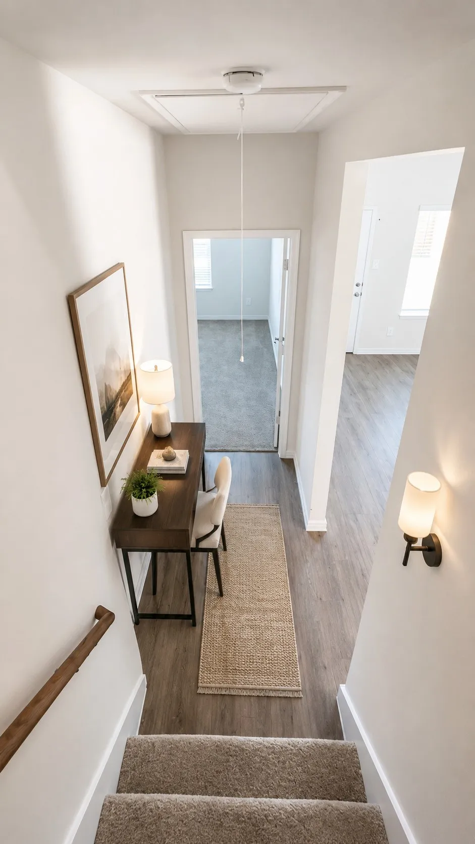 Carpeted staircase with a wood handrail leading to a landing featuring wood-finish flooring