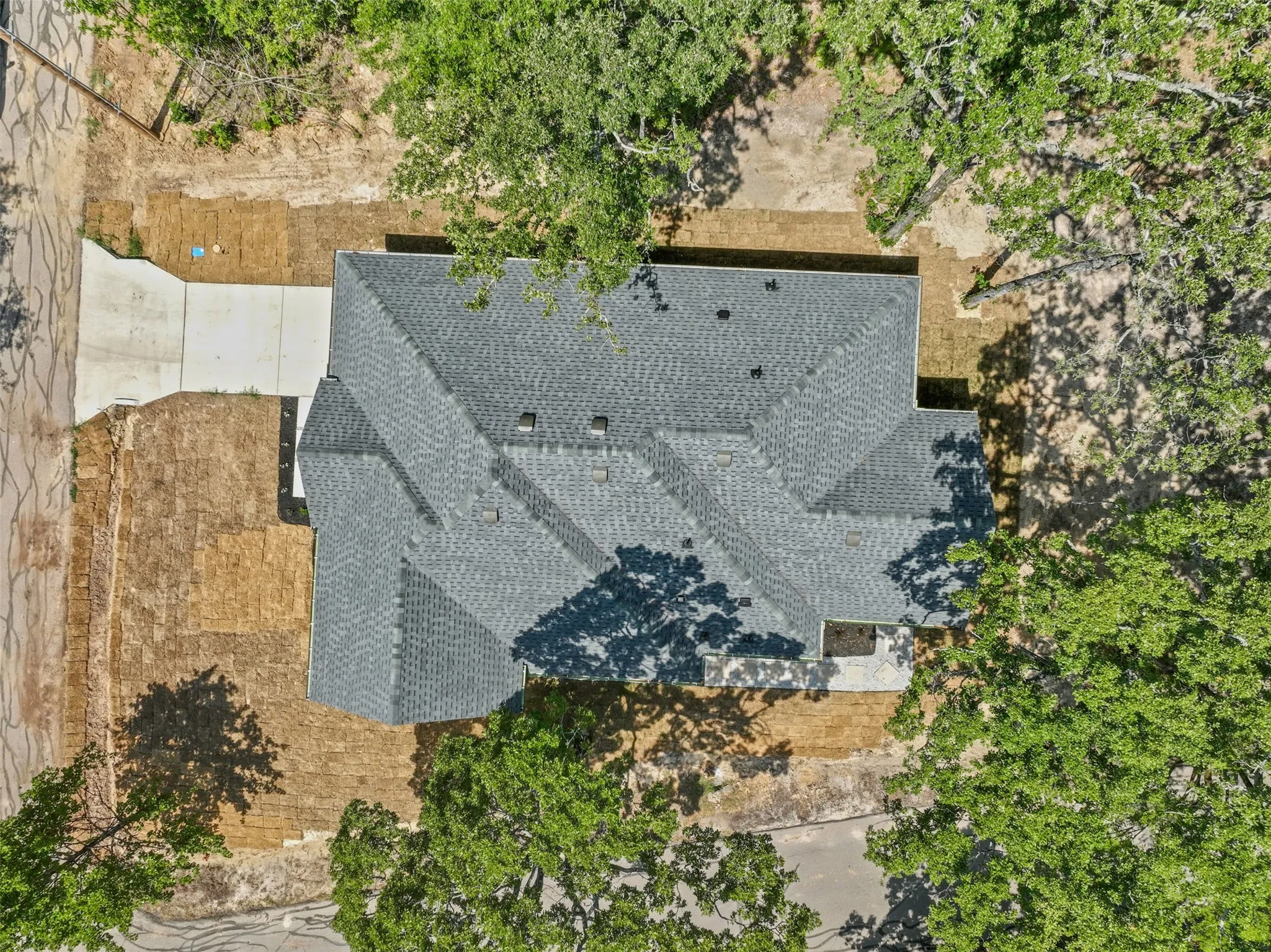 Asphalt shingle roof with multiple gables and a concrete driveway