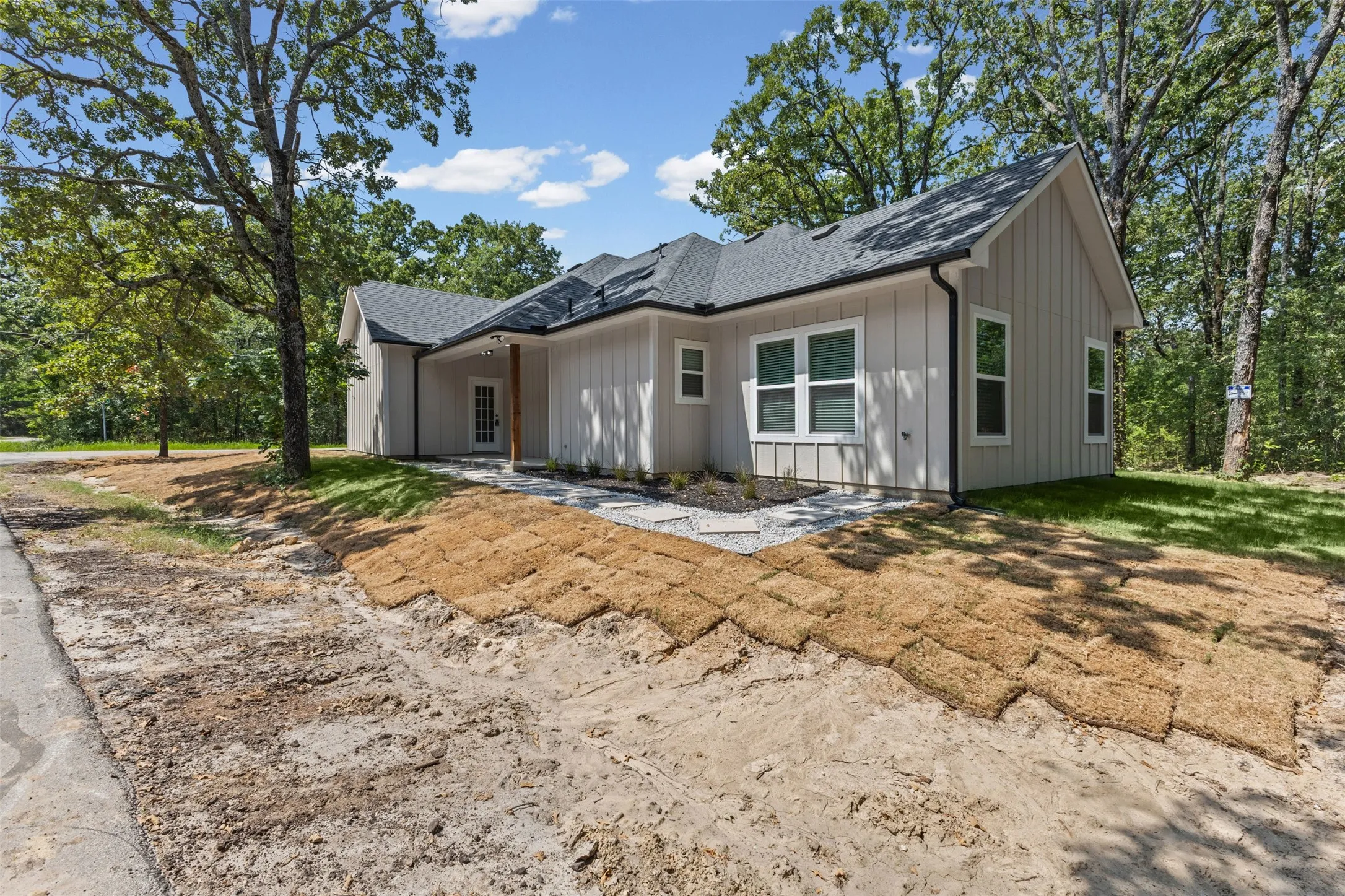 Contemporary-style residence featuring a dark shingle roof, light-toned vertical siding, and multiple windows