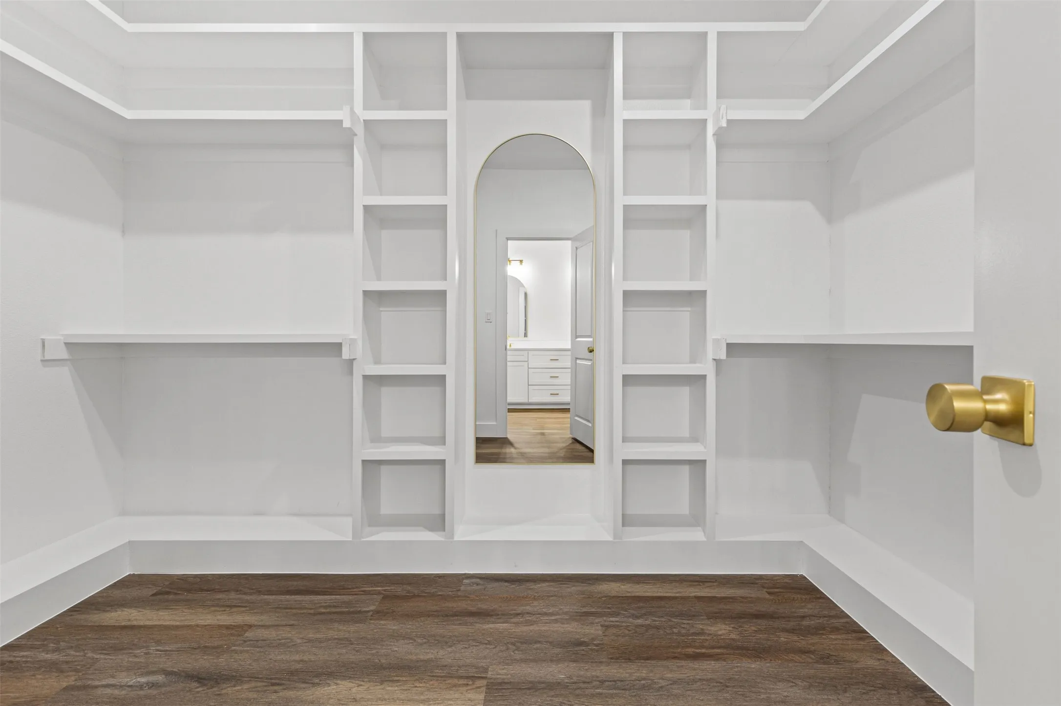 Walk-in closet featuring built-in shelving, hanging rods, and wood-finish flooring