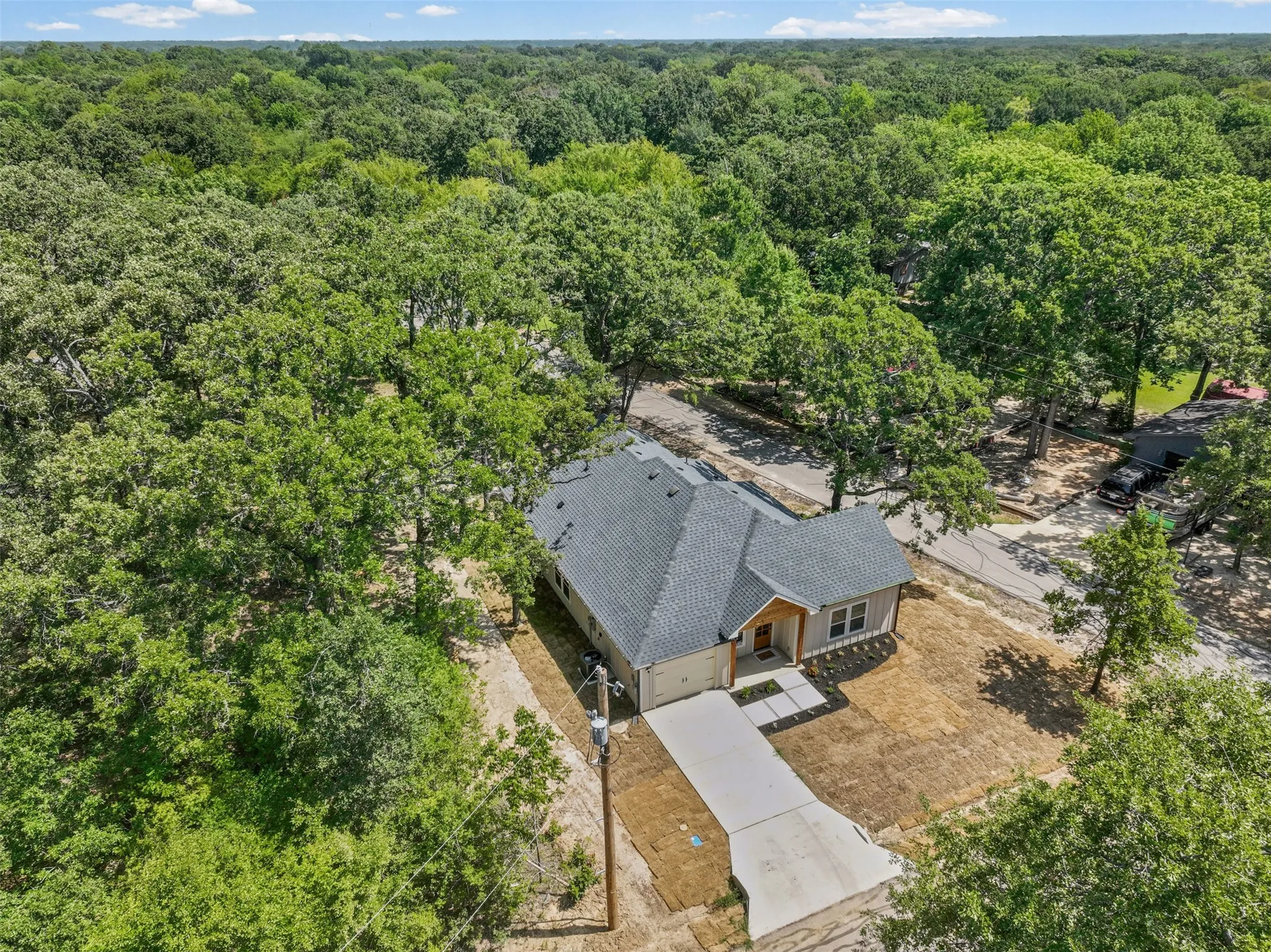 New construction home featuring a light gray exterior, dark gray shingled roof, and an attached two-car garage
