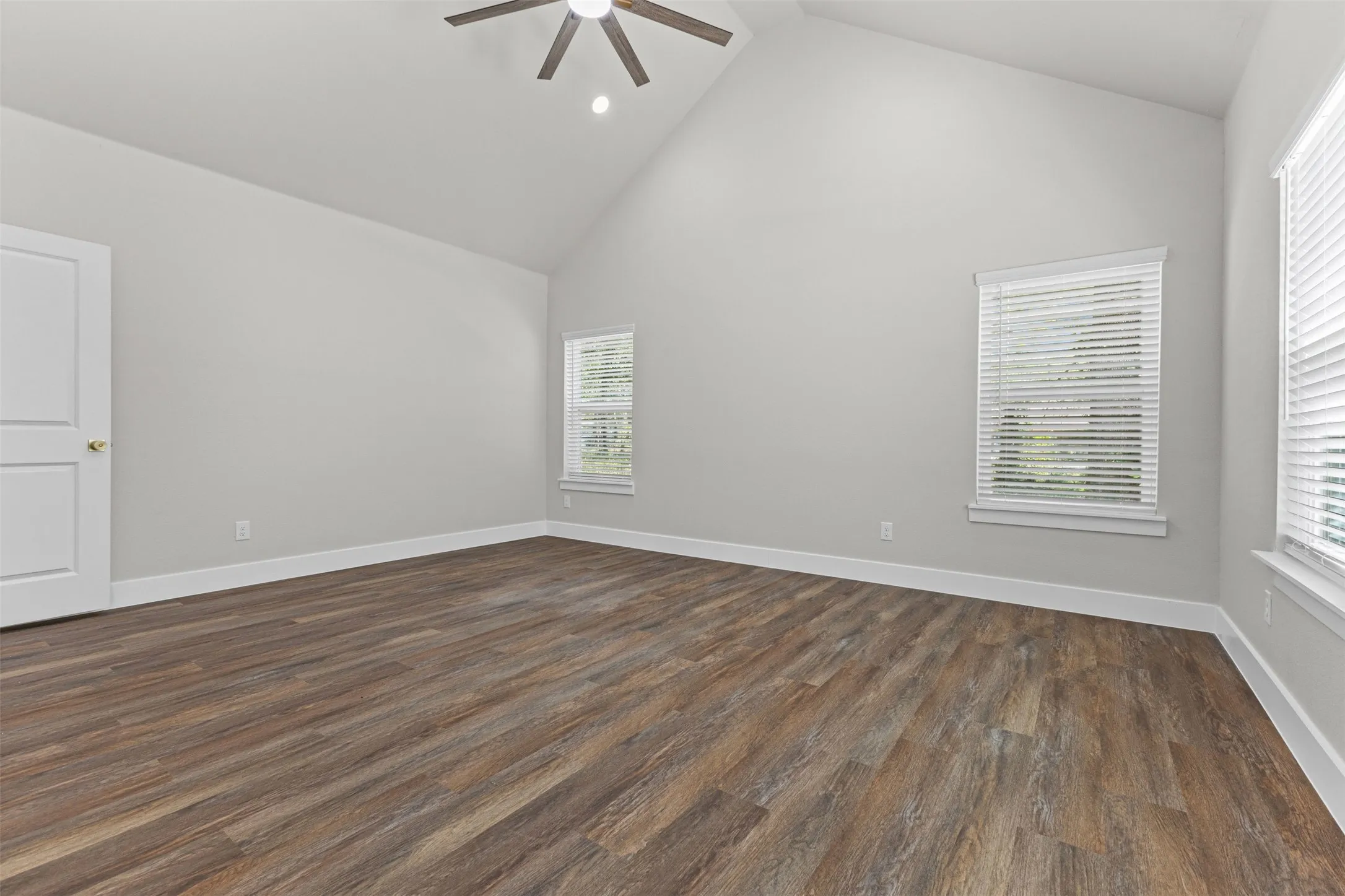 Spacious room featuring vaulted ceilings, wood-finish flooring, and white trim