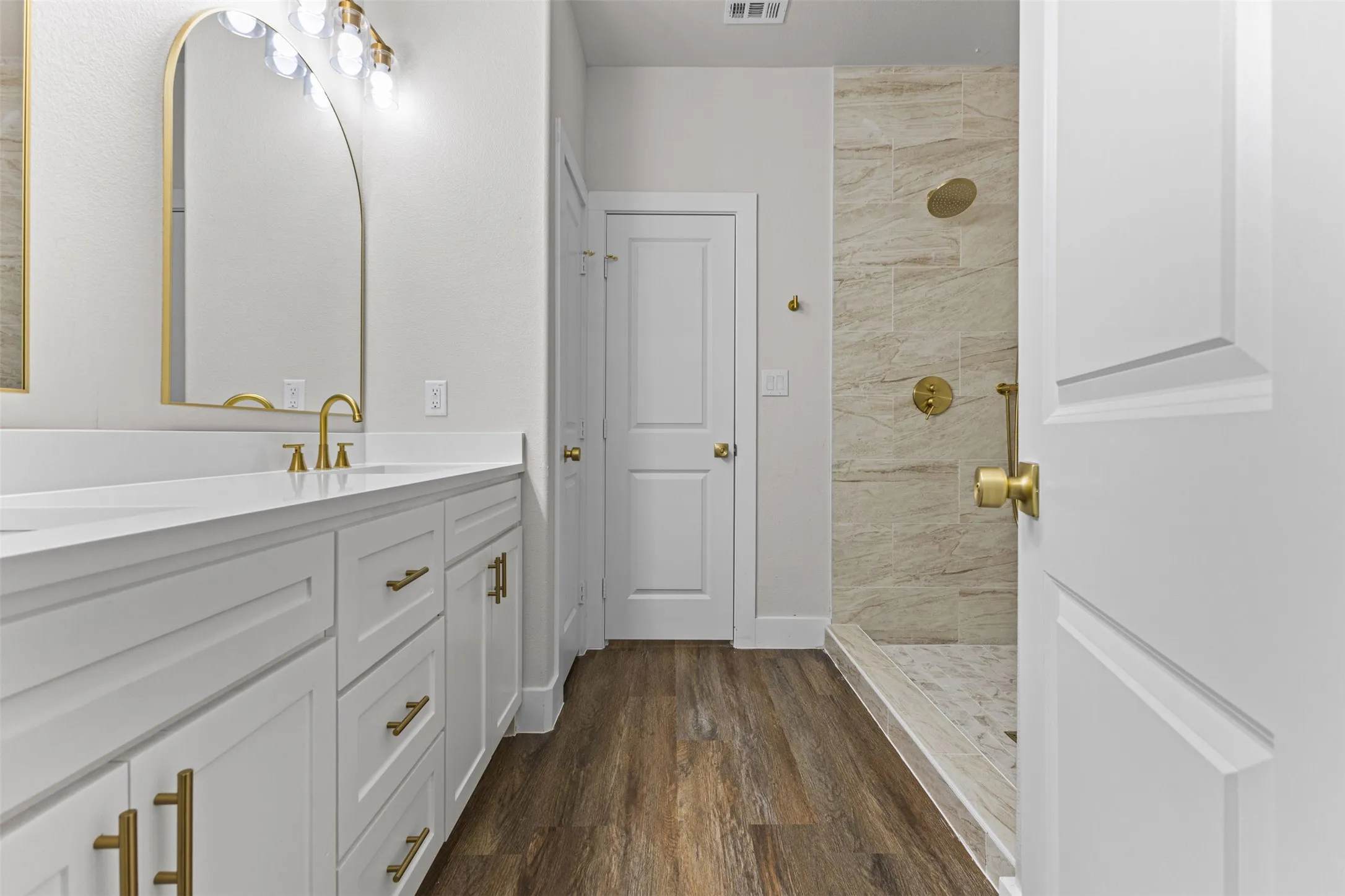 Contemporary bathroom featuring a double vanity with white cabinetry, gold hardware, and a quartz countertop