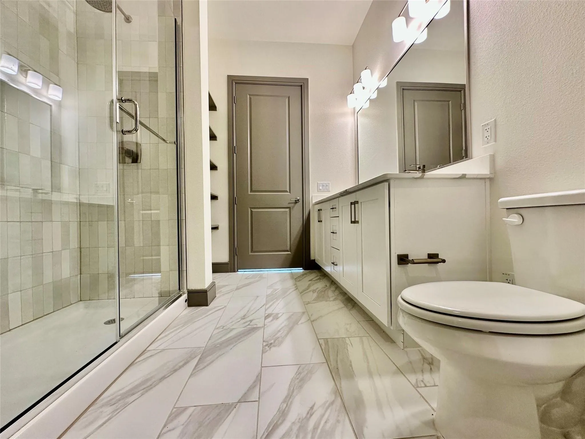 Contemporary bathroom featuring a spacious glass-enclosed shower, dual vanity with white cabinetry, a large mirror, and tiled flooring