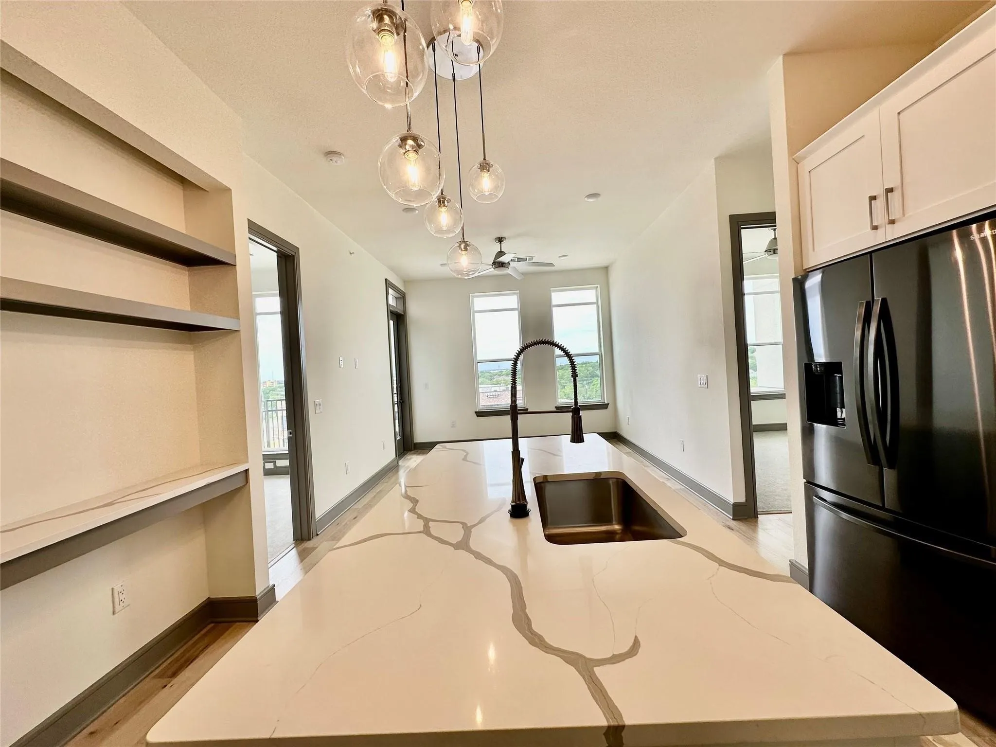 Kitchen island with a light-toned countertop and striking gray veining, featuring an undermount stainless steel sink and a matte black gooseneck faucet