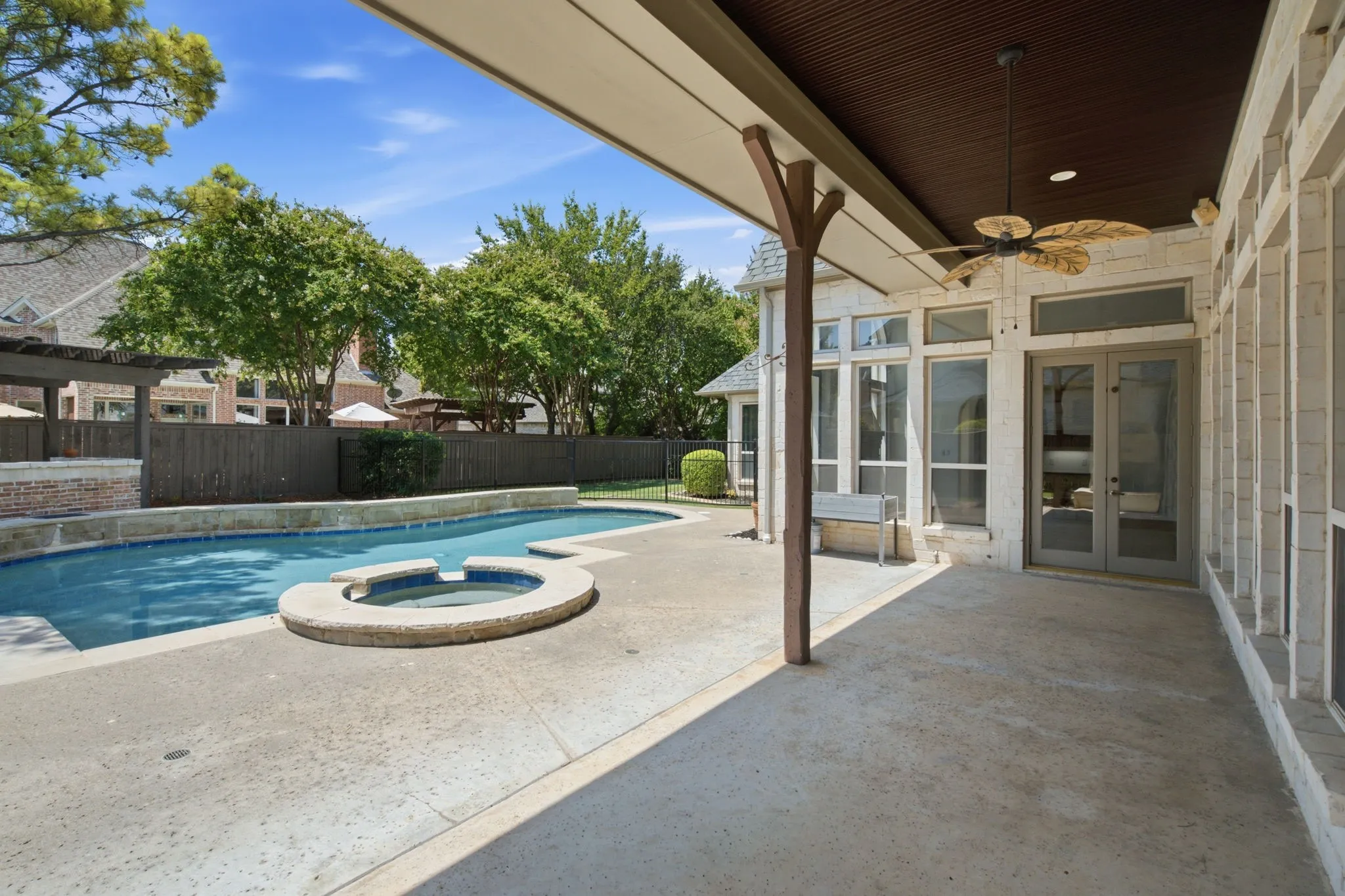 Covered patio with a ceiling fan, dual glass panel doors, and full-height windows