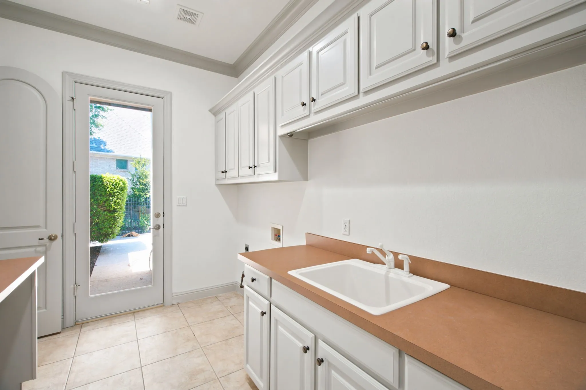Full-light door, tile flooring, white cabinetry, integrated sink, and brown countertops