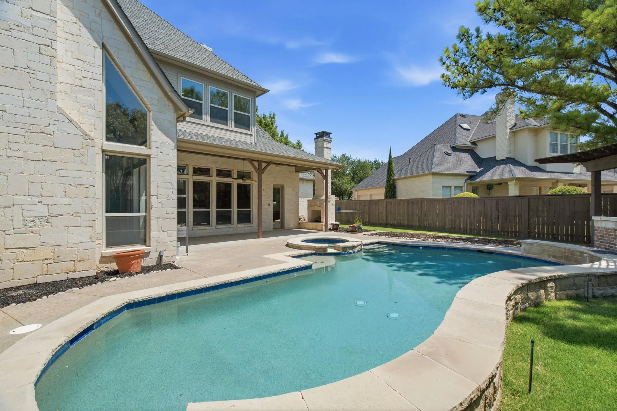 Exterior stonework, expansive patio, private swimming pool, built-in spa, and covered outdoor living area