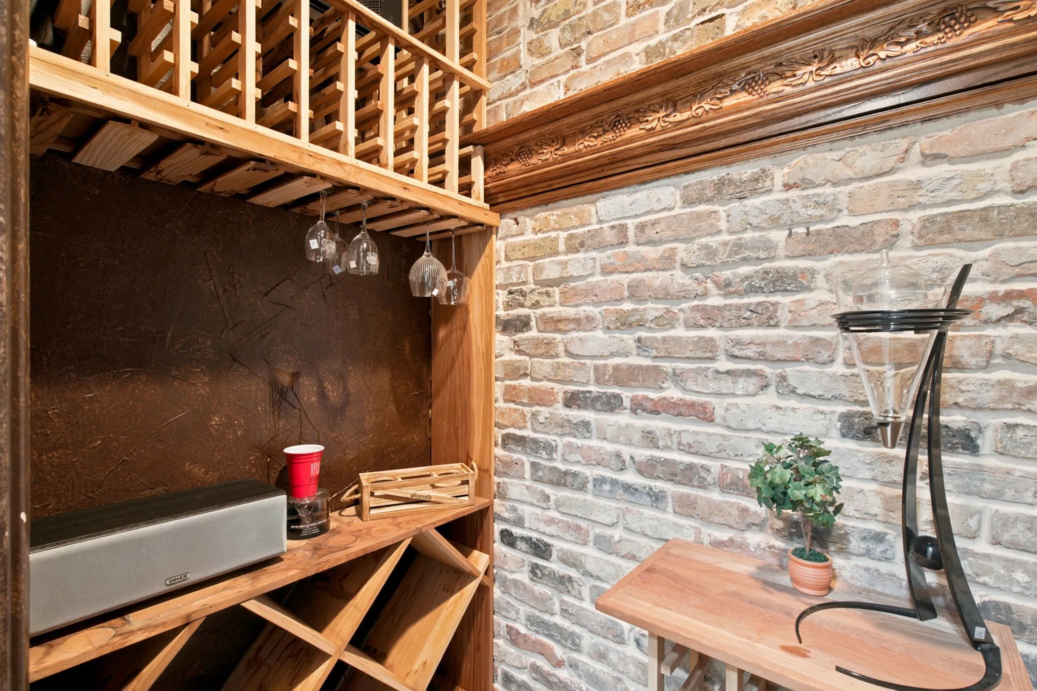 Exposed brick wall with decorative wood trim, built-in wooden wine rack, and a dedicated hanging stemware storage