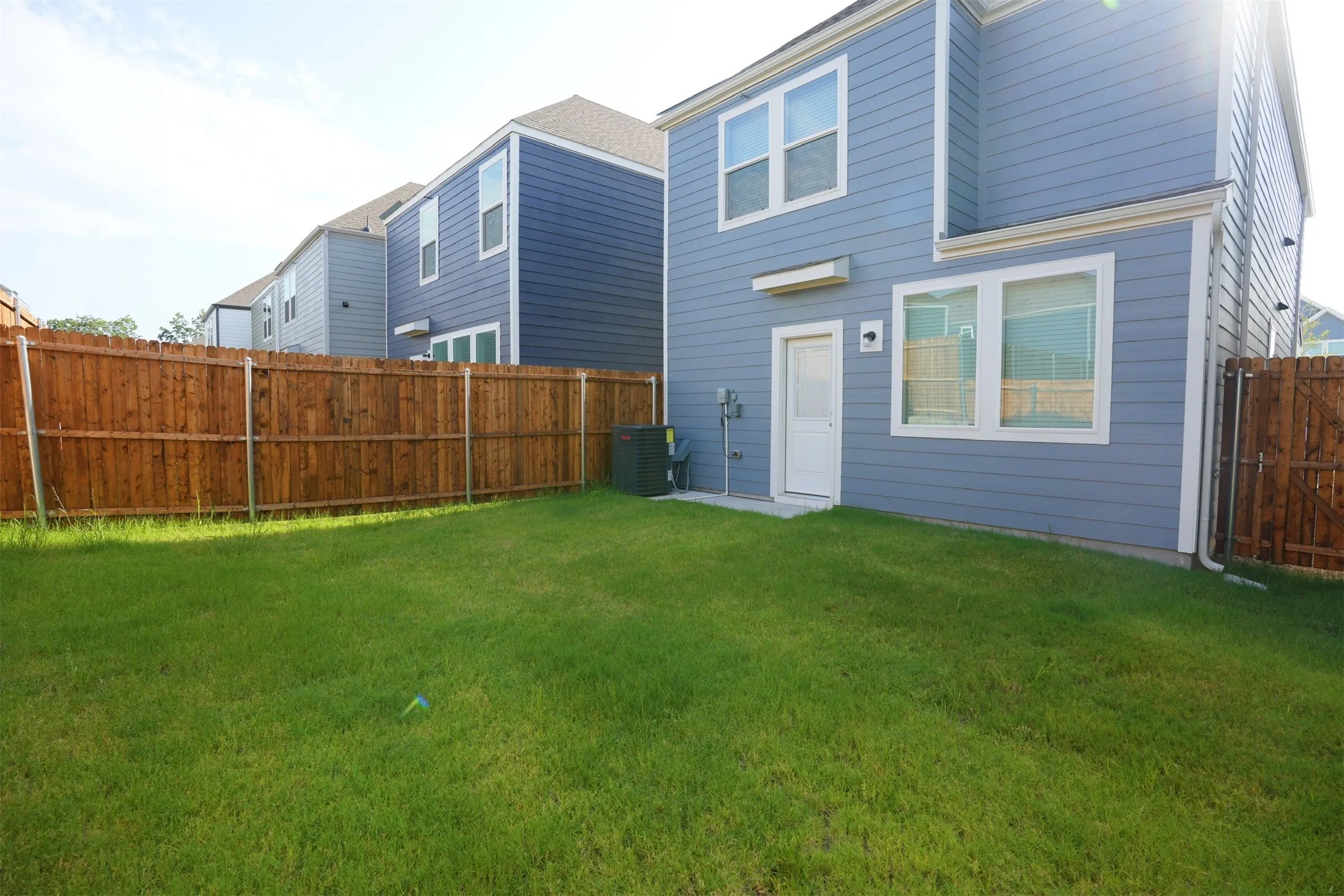 Private backyard featuring a full wood fence, green lawn, and exterior access door