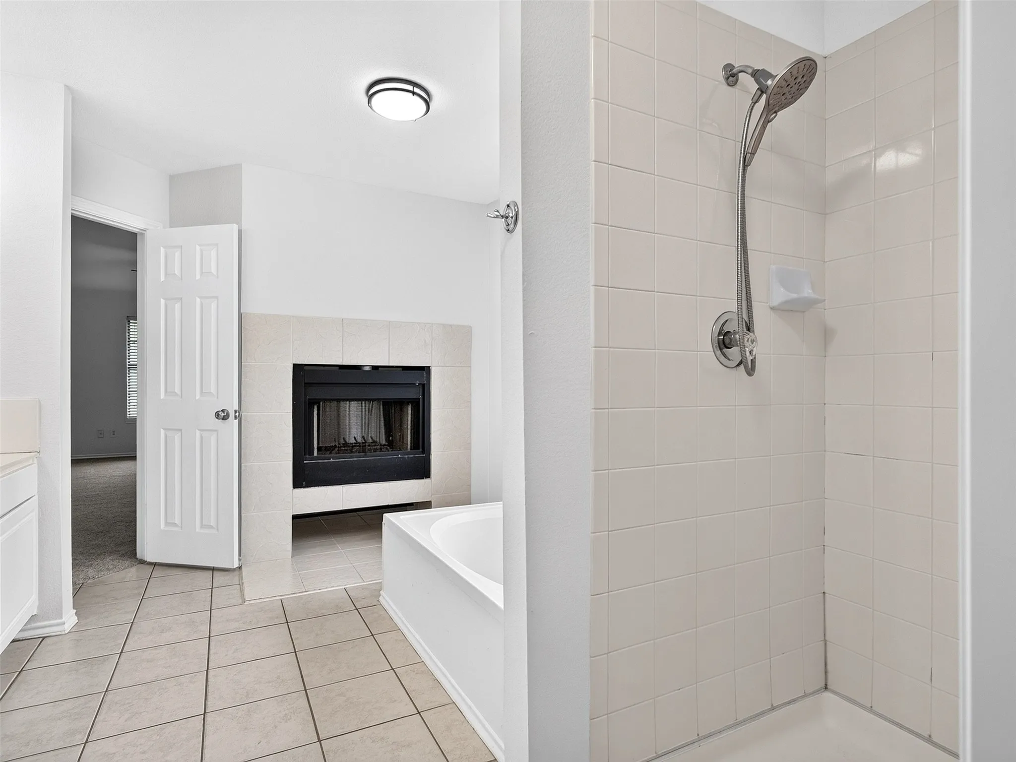 Bathroom featuring a tiled shower, built-in bathtub, and a fireplace with a tiled surround