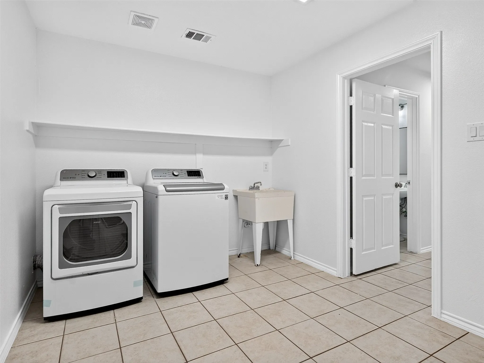 Dedicated utility space featuring tile flooring and a built-in utility sink