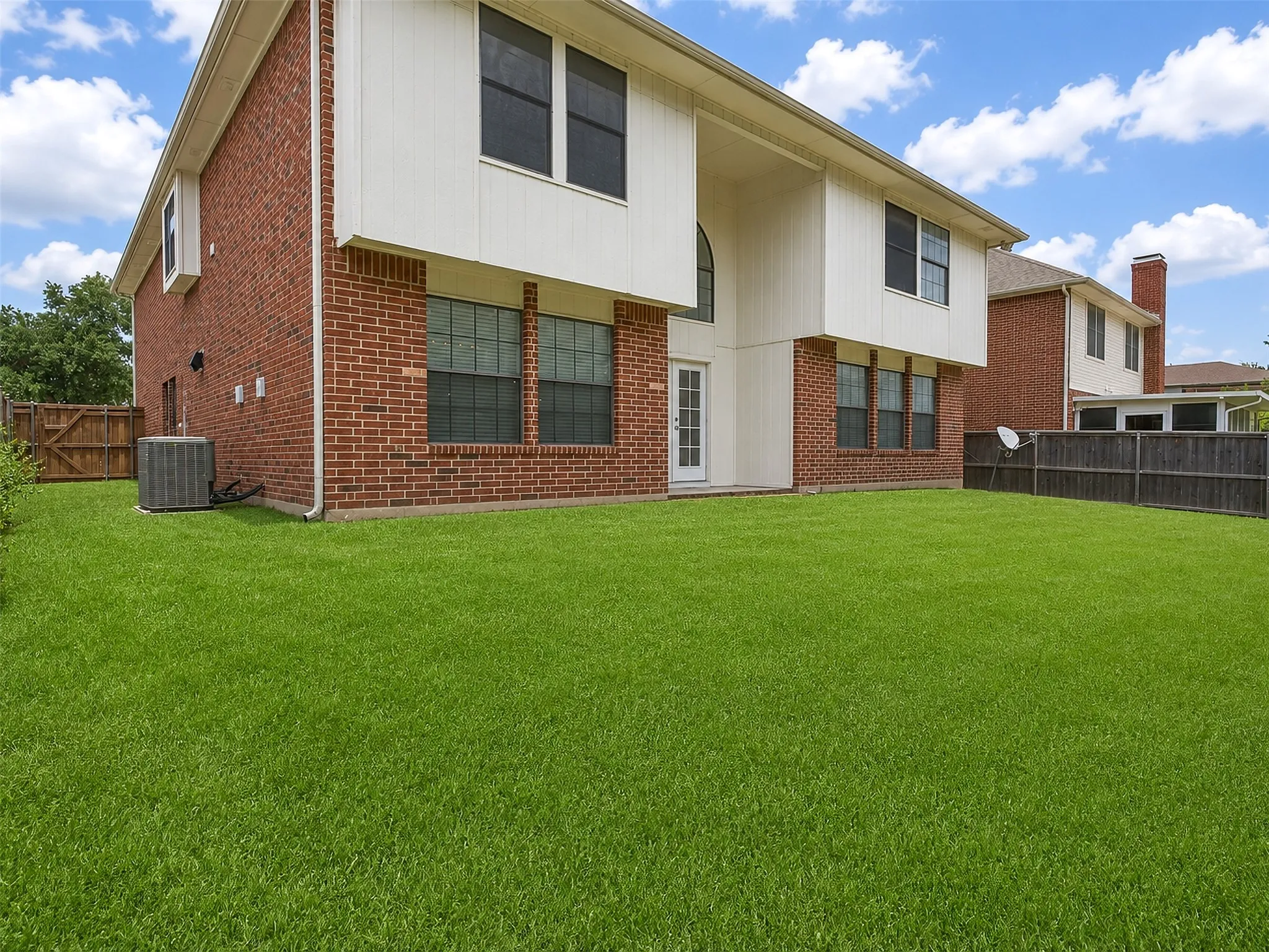 Expansive green lawn with a two-story brick and siding exterior