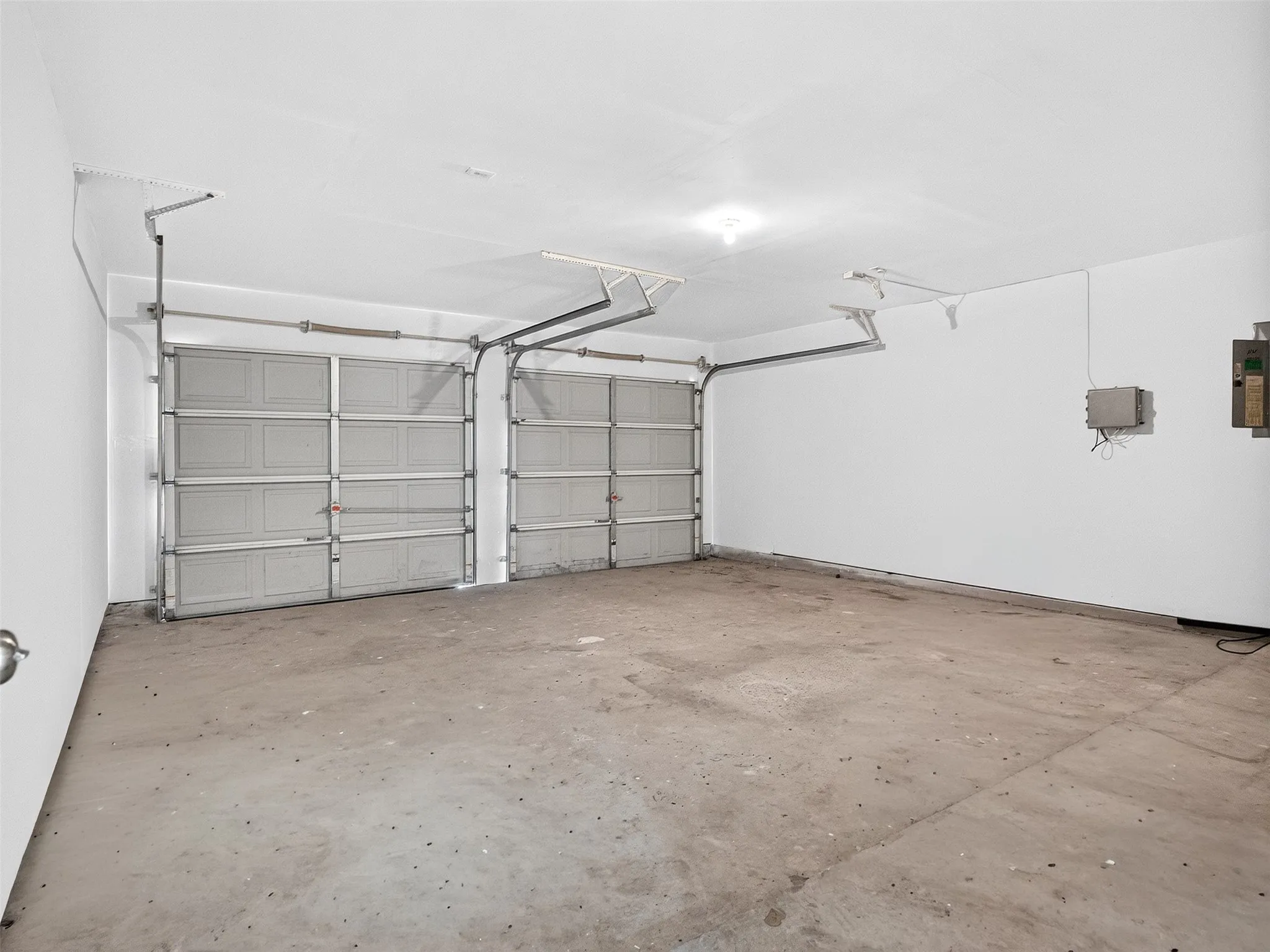 Two-car garage featuring a concrete floor, white walls, and overhead lighting