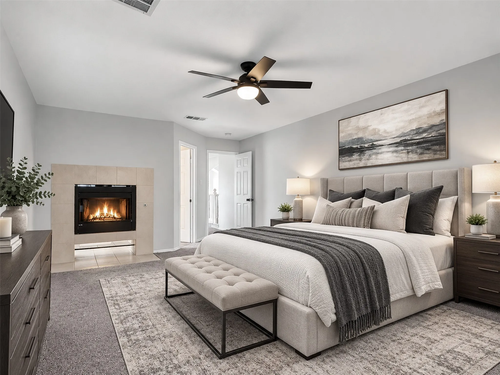Spacious bedroom featuring a built-in fireplace with tile surround, ceiling fan, carpet flooring, and light-toned wall paint