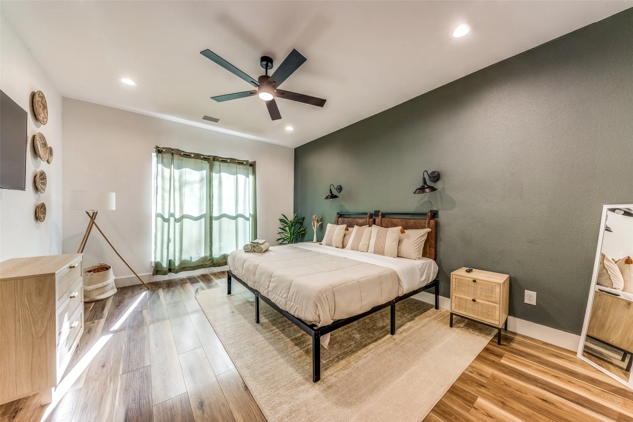 Spacious room featuring wood-finish flooring, a contemporary ceiling fan, and recessed lighting
