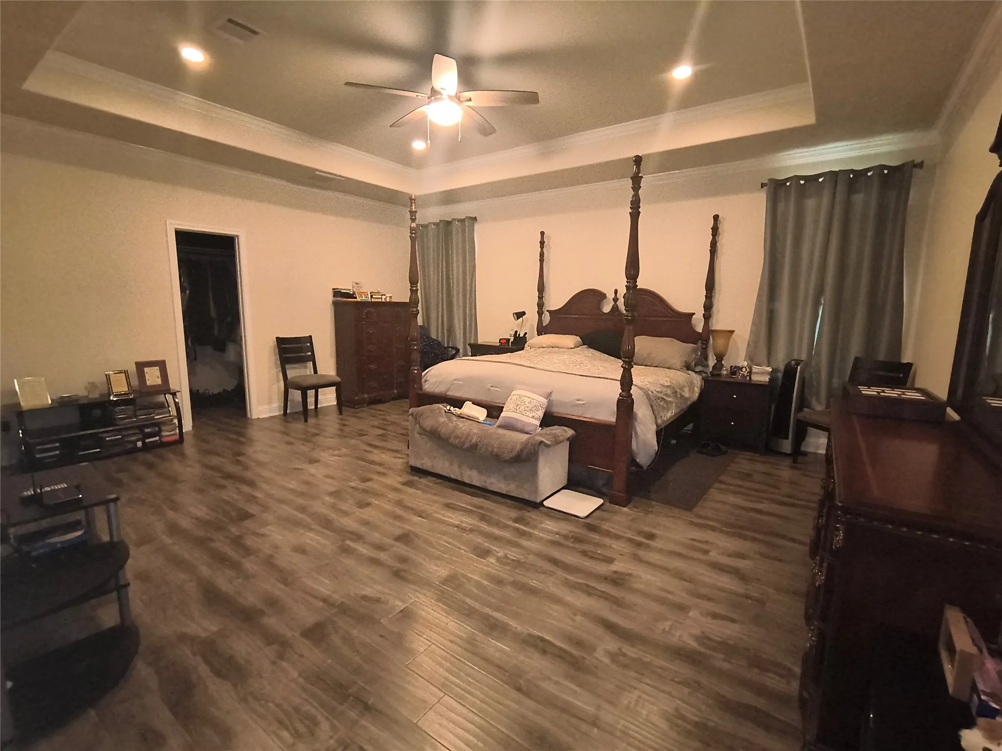 Spacious bedroom featuring wood-finish flooring and a tray ceiling with recessed lighting