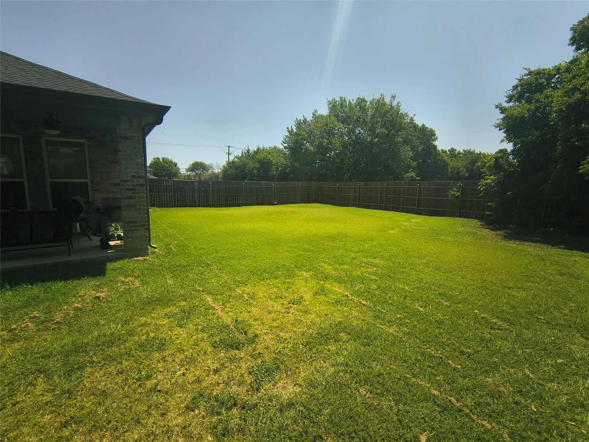 Spacious backyard featuring a wood privacy fence and mature perimeter trees