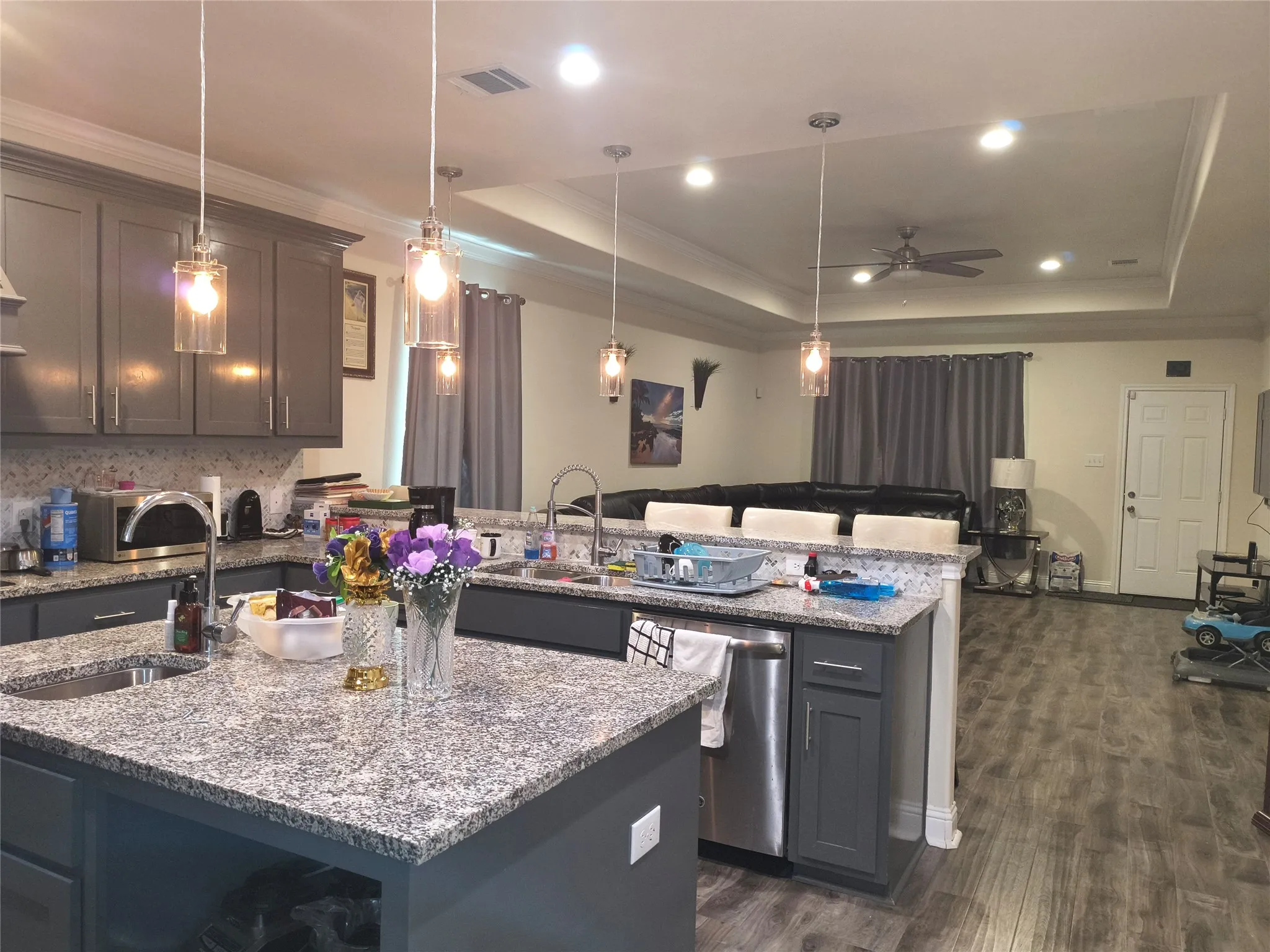 Open-concept kitchen featuring gray cabinetry, granite countertops, and a complementary backsplash
