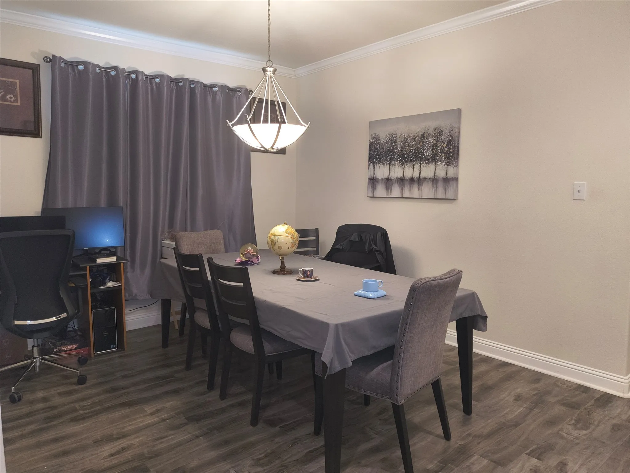 Spacious room featuring wood-finish flooring, crown molding, and baseboards