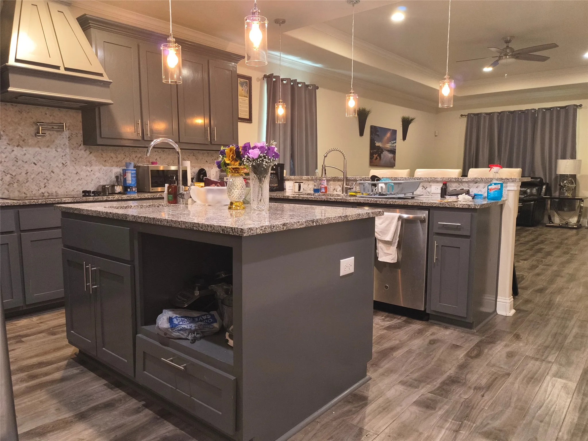 Kitchen featuring a large island with an undermount sink, granite countertops, and grey cabinetry