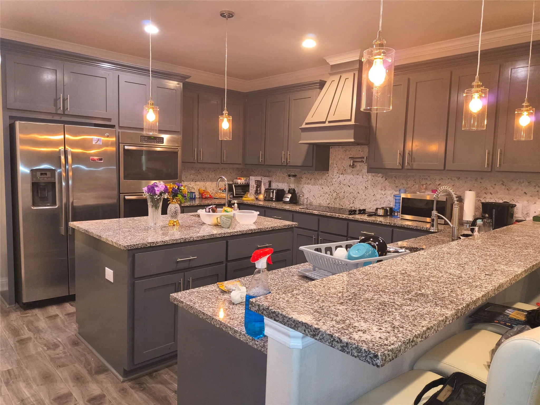 Kitchen featuring dual islands, stainless steel appliances, grey cabinetry, granite countertops, and mosaic tile backsplash