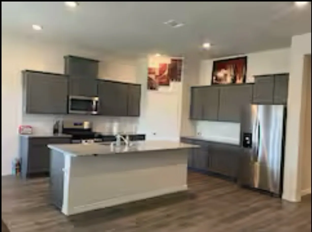 Kitchen featuring stainless steel appliances, dark wood-style flooring, light countertops, and a sink