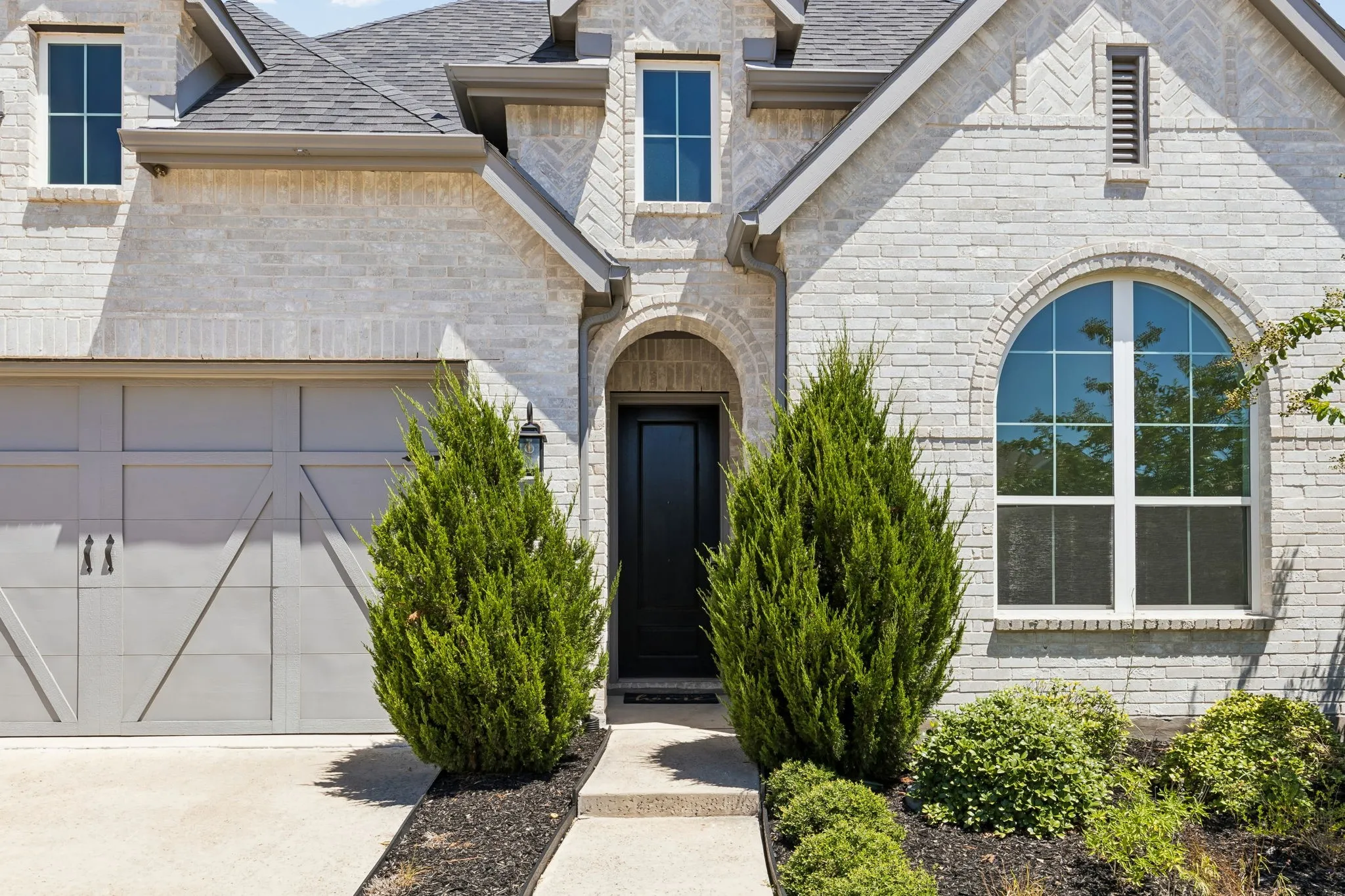 Beautiful entry with solid wood front door and mature landscaping