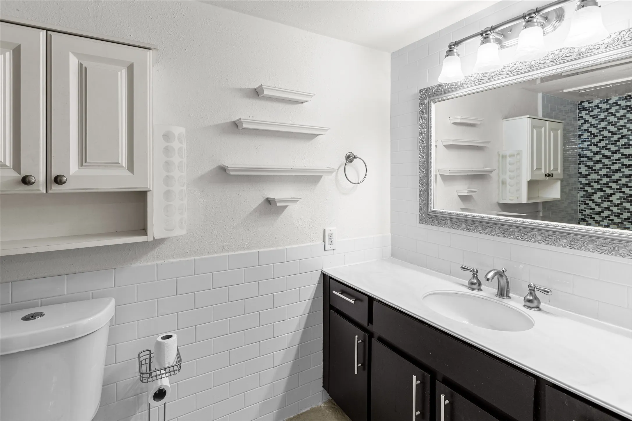 Bathroom featuring a vanity with dark wood-finish cabinetry, white countertop, and an undermount sink with brushed nickel fixtures